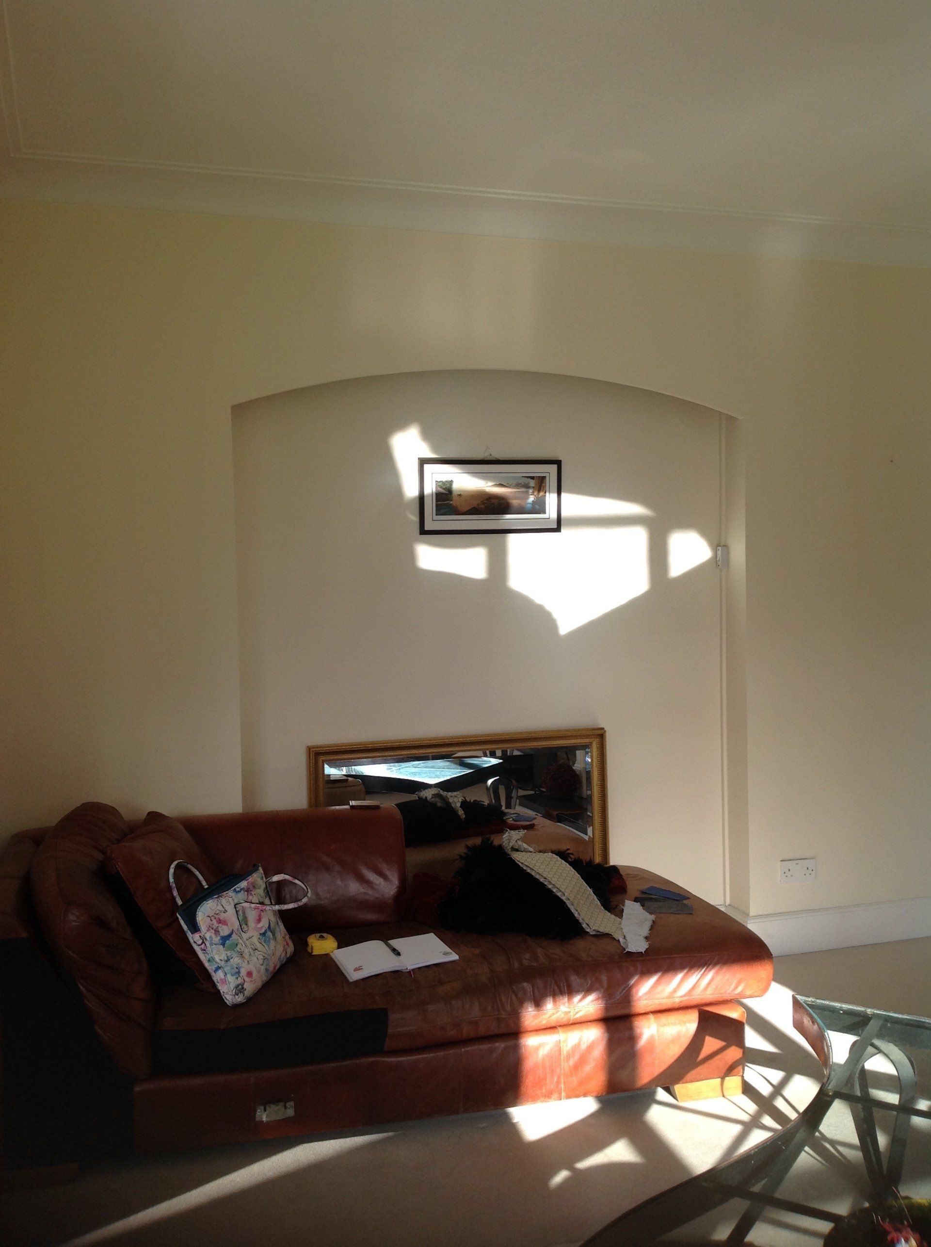 A living room with a brown leather couch and a mirror