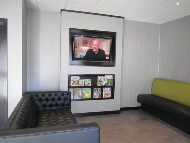 A living room with a couch and a television on the wall