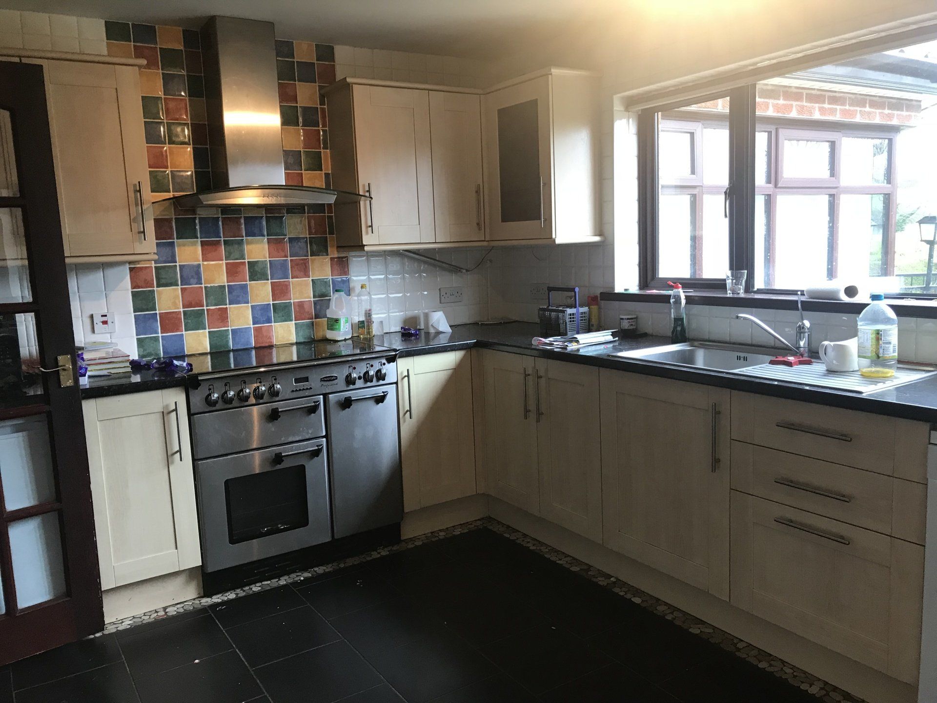 A kitchen with stainless steel appliances and colorful tiles on the wall.