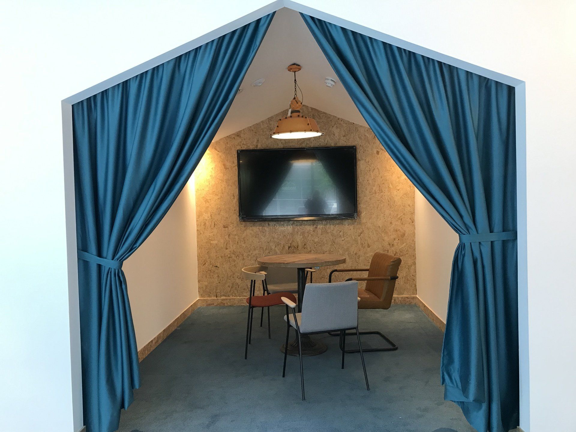 A room with a table and chairs and a television on the wall.