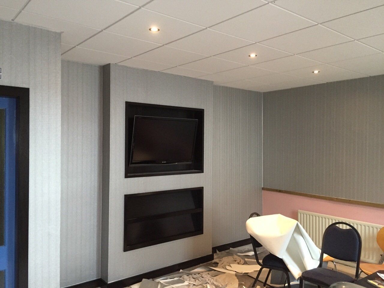 A room with a chair and a television on the wall