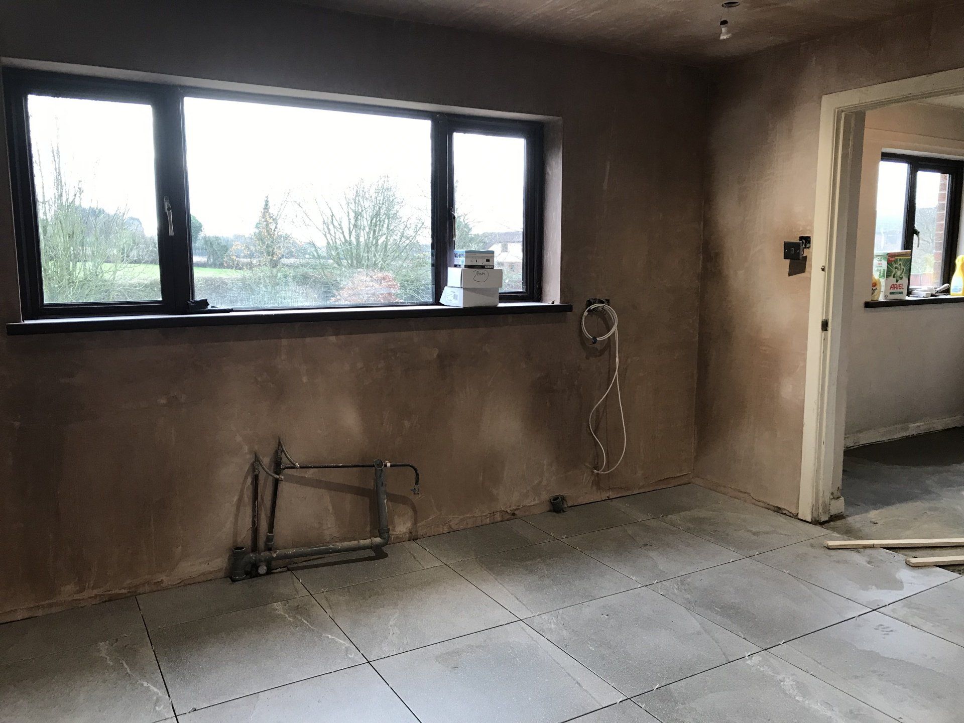 An empty room with a window and a saw on the floor.