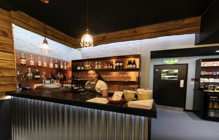 A man is standing behind a bar in a restaurant.
