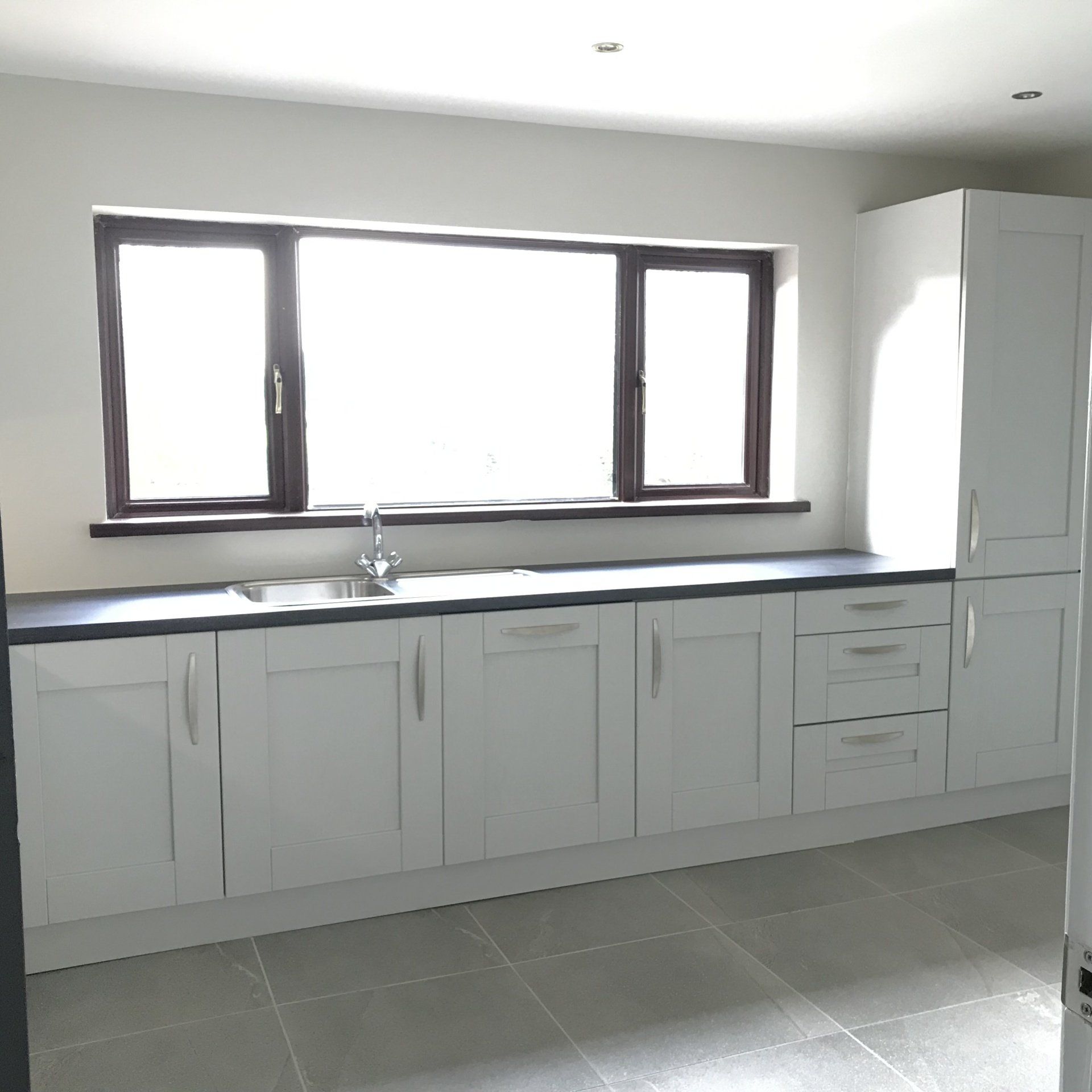 A kitchen with white cabinets and a large window