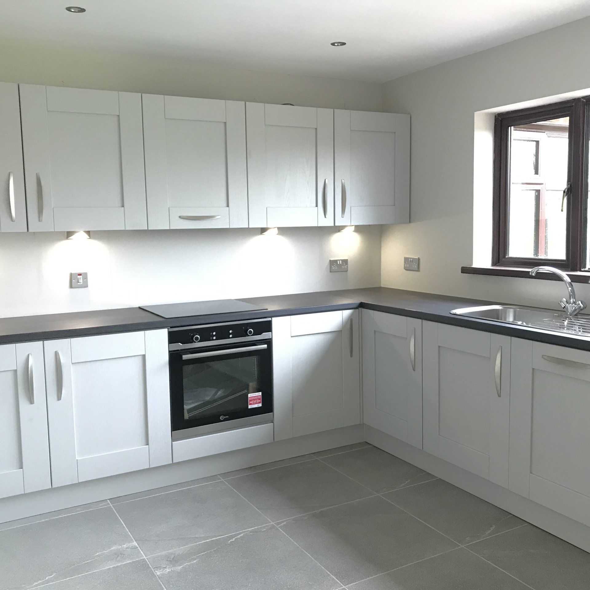 An empty kitchen with white cabinets and a window