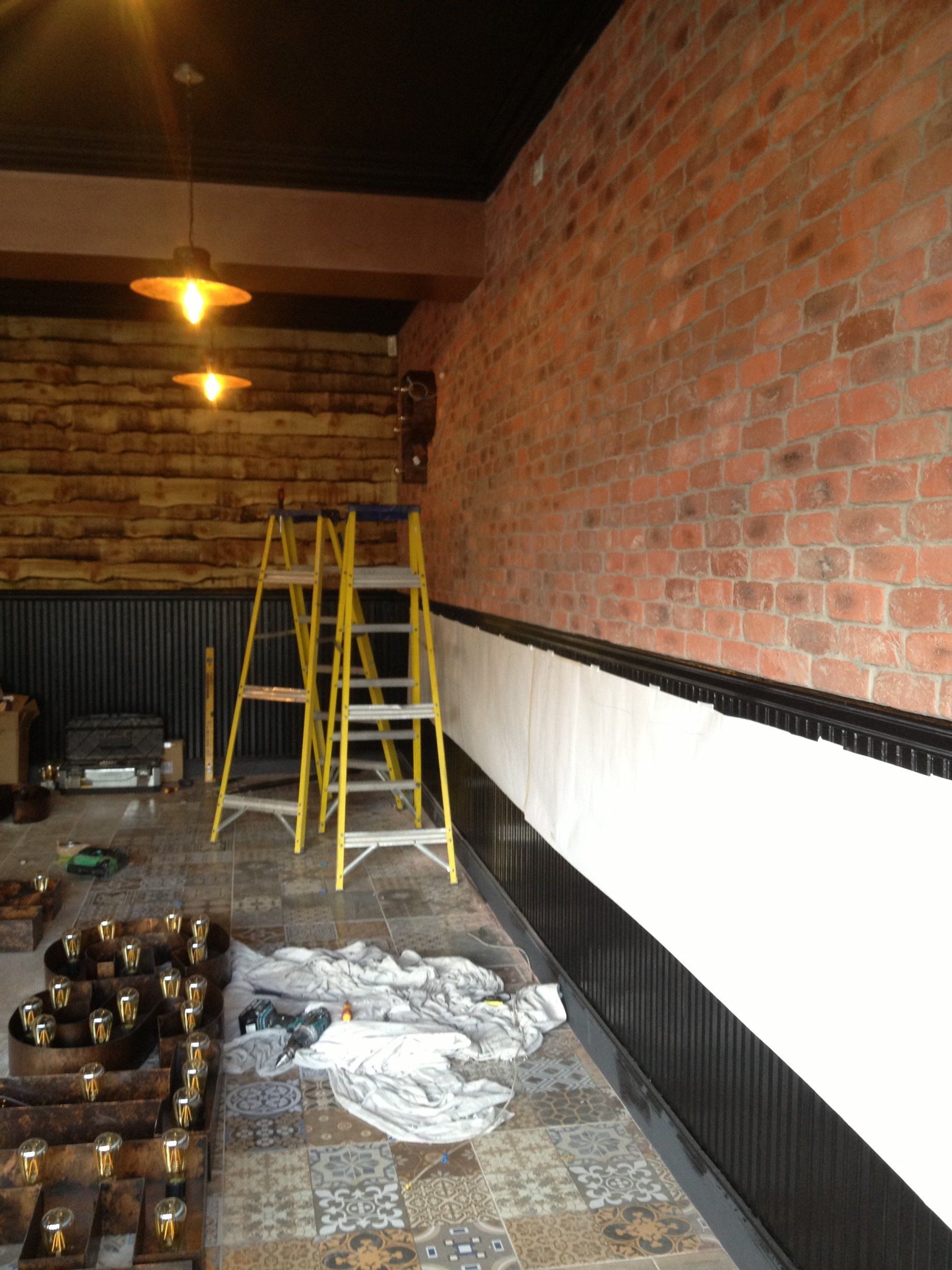 A room with a brick wall and a ladder on the floor