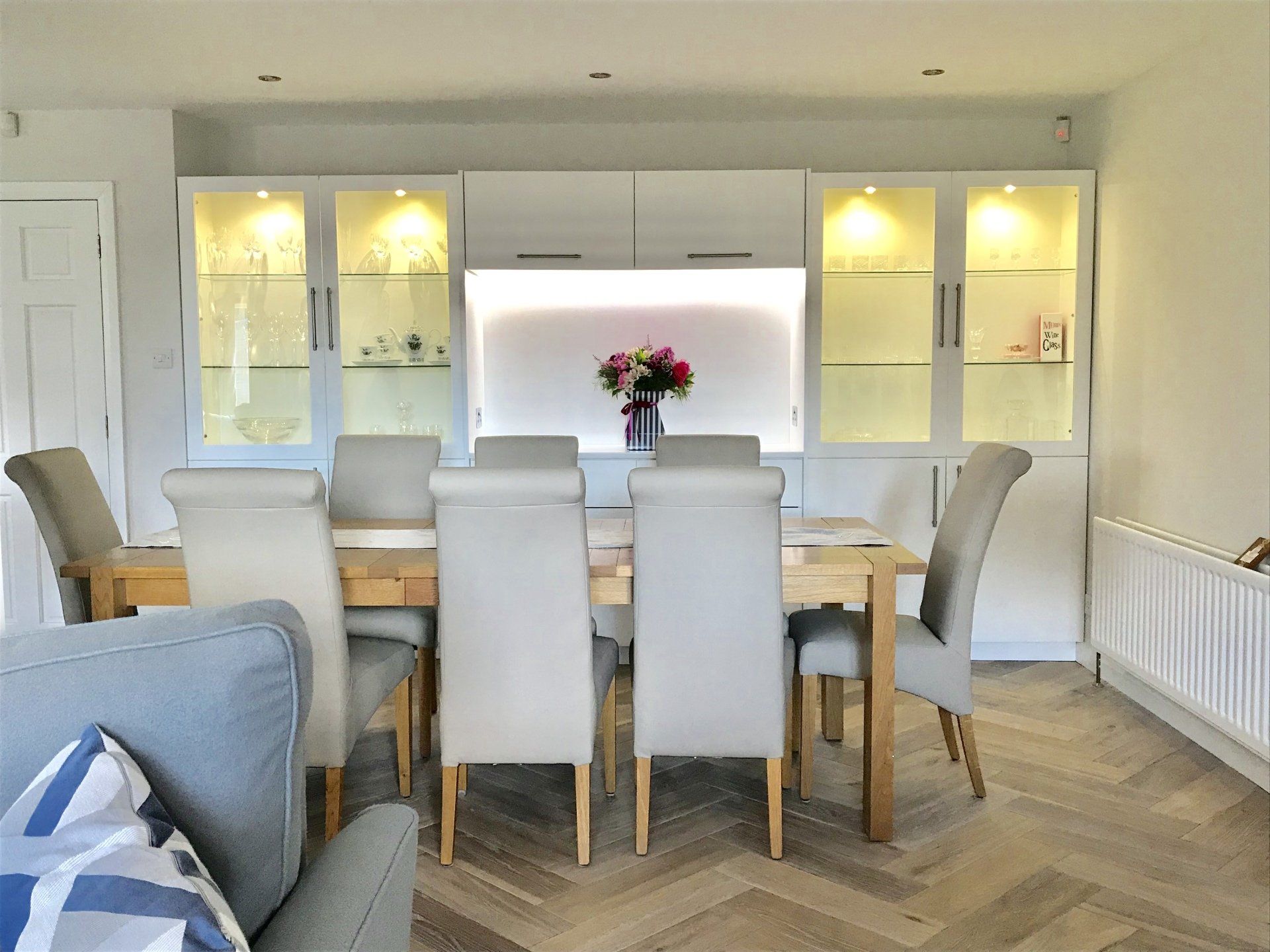 A dining room with a table and chairs and a vase of flowers on the wall.