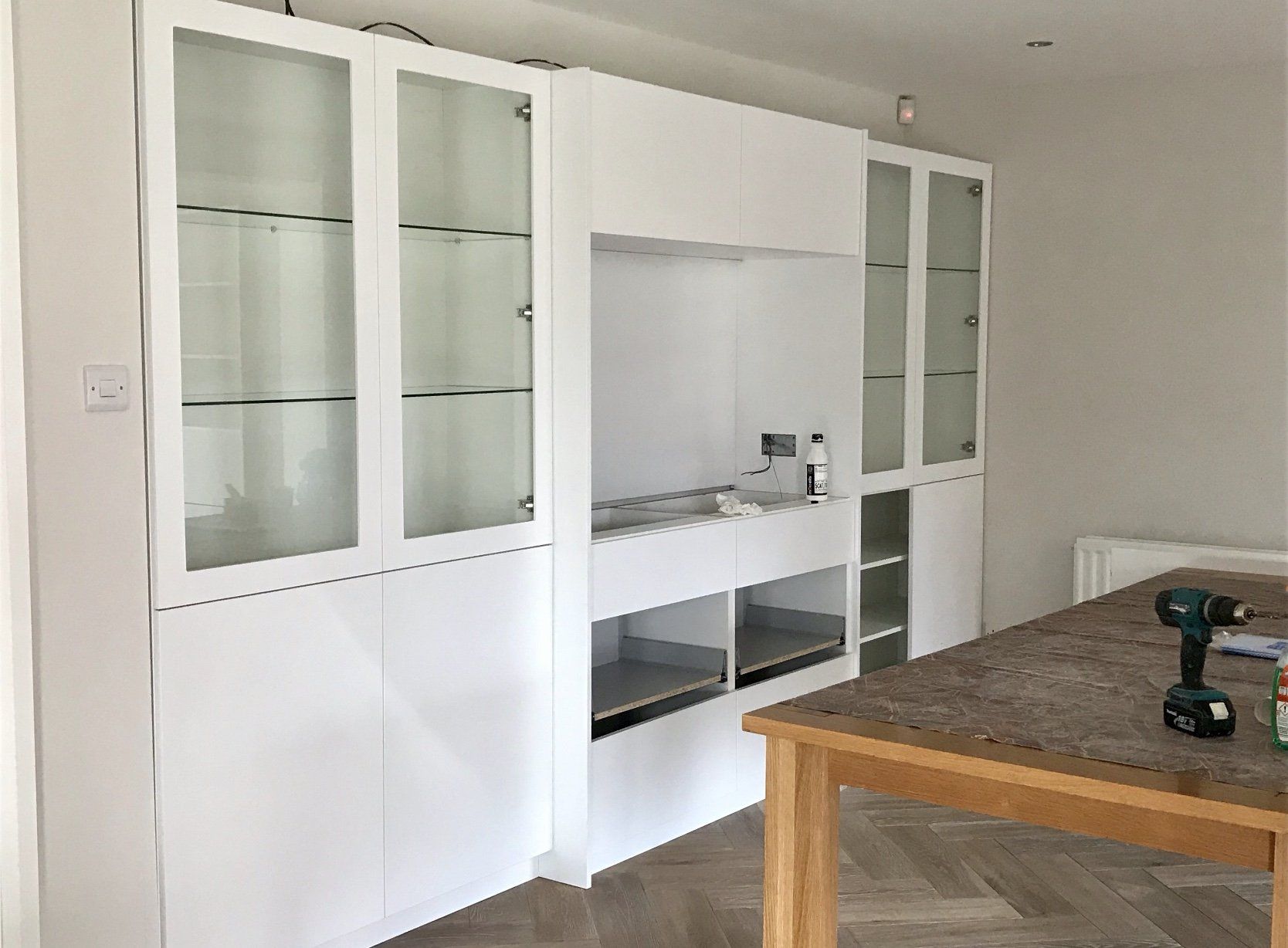 A living room with white cabinets and a wooden table.