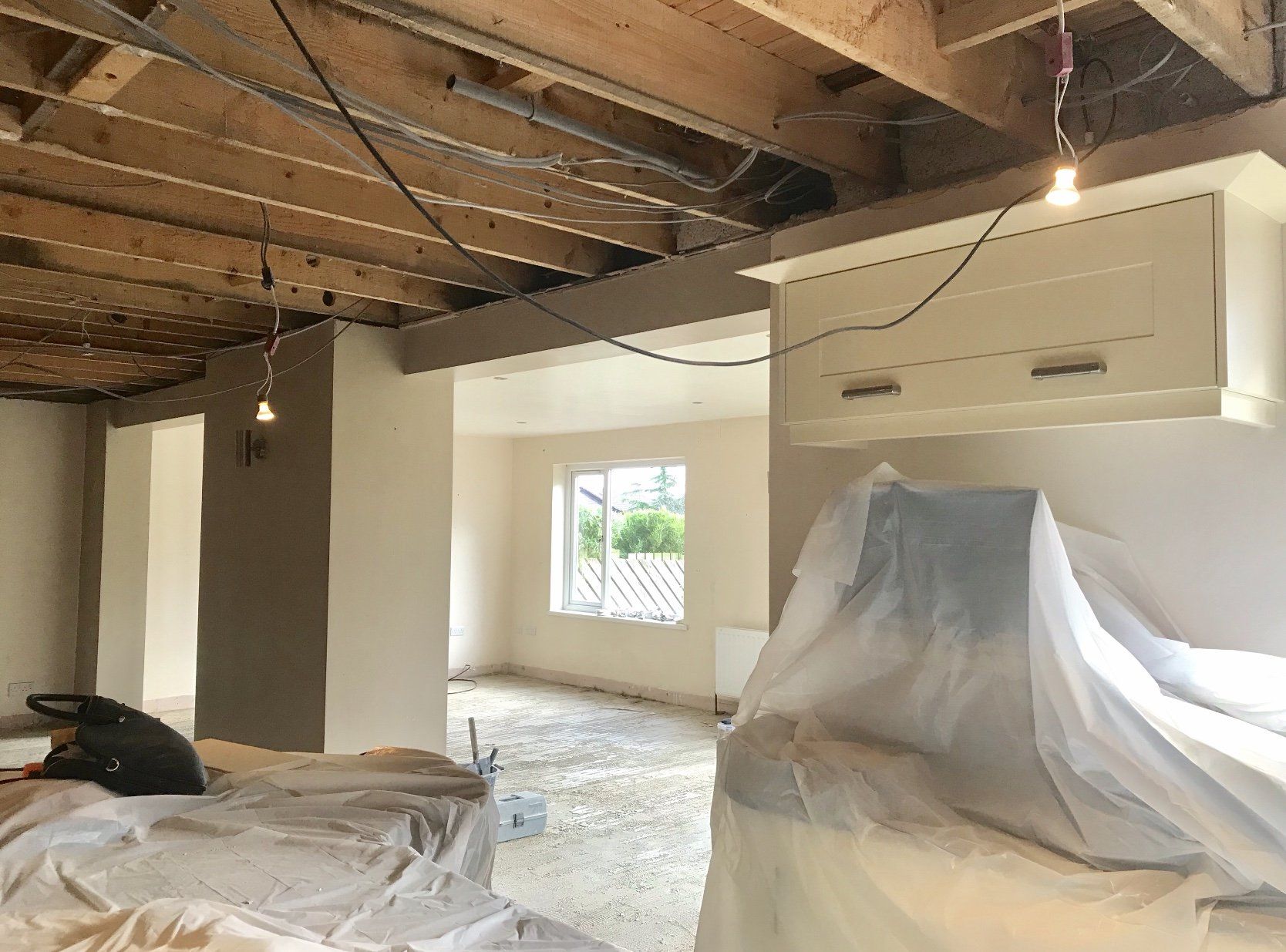 A room with a ceiling that is being remodeled and covered in plastic.