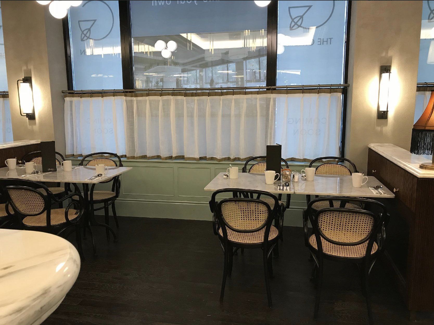 A restaurant with tables and chairs and a large window.