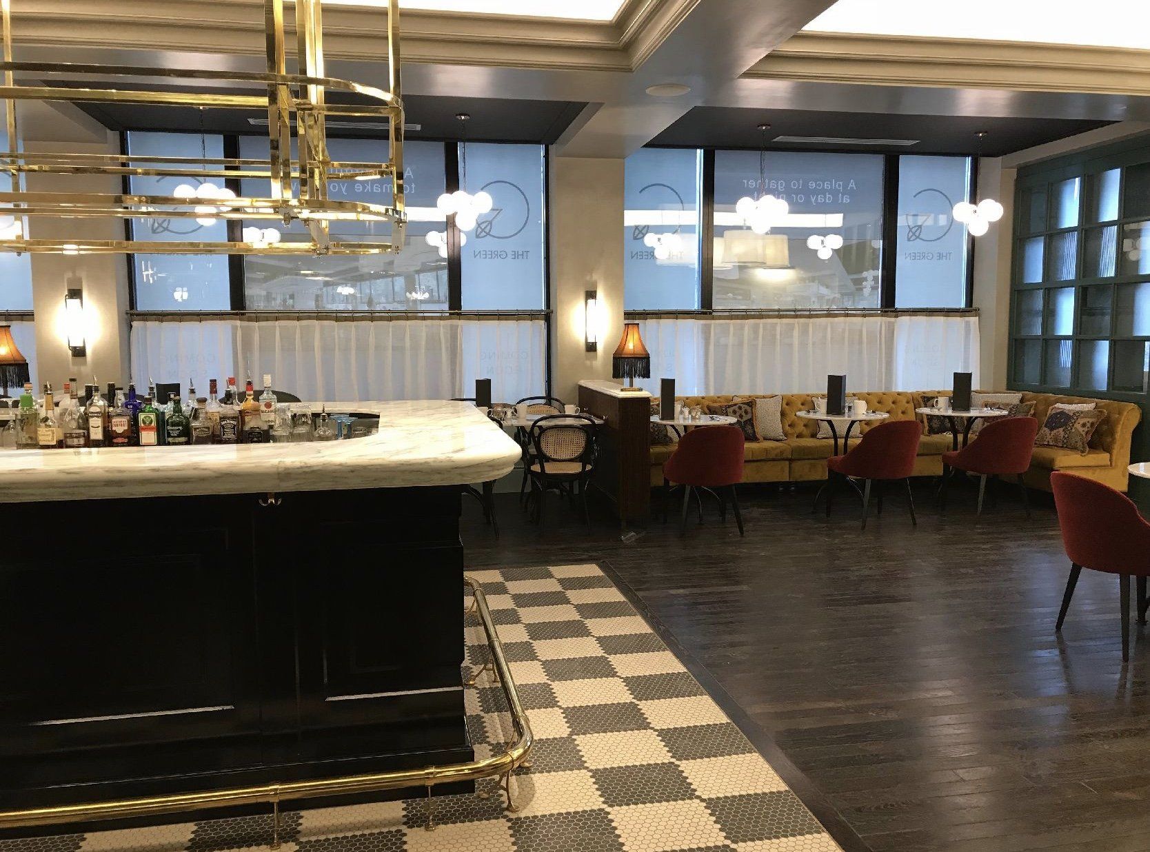 A restaurant with a checkered floor , tables , chairs and a bar.