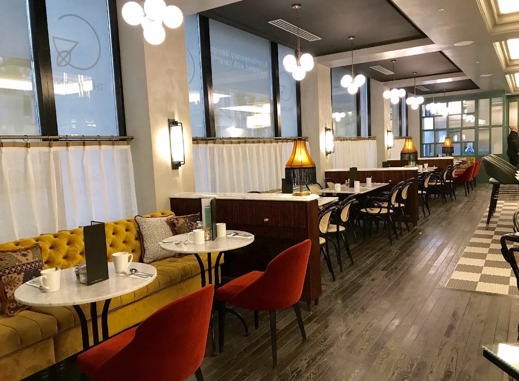 A restaurant with tables and chairs and a yellow couch.