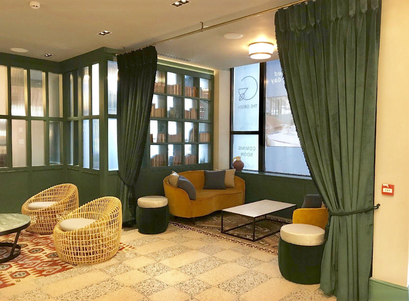 A living room with a couch , chairs , tables and curtains.