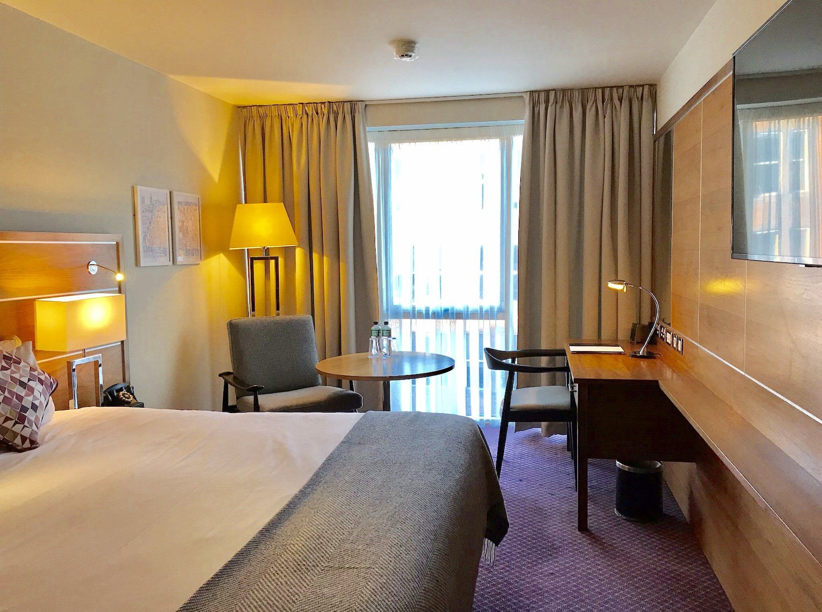 A hotel room with a king size bed and a desk