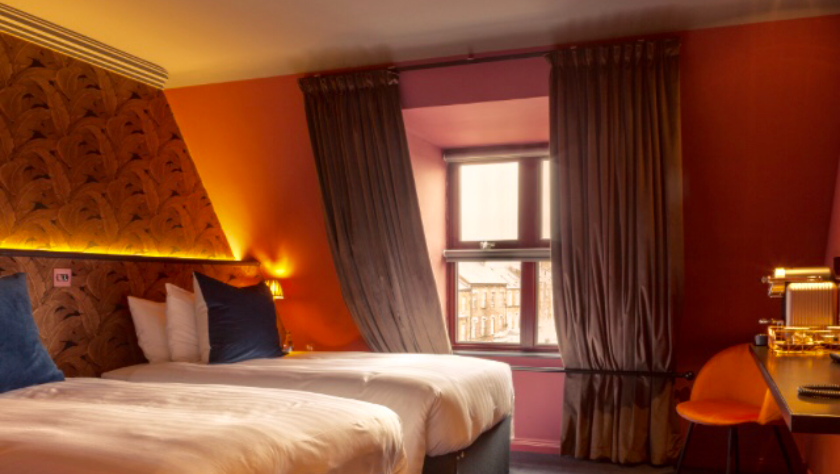 A hotel room with two beds , a desk and a window.