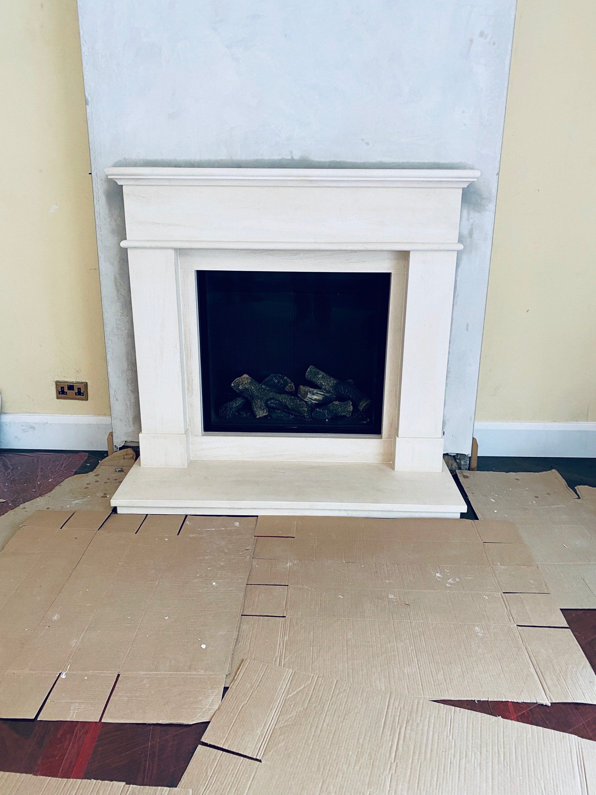 A fireplace is sitting on top of a cardboard box in a room.