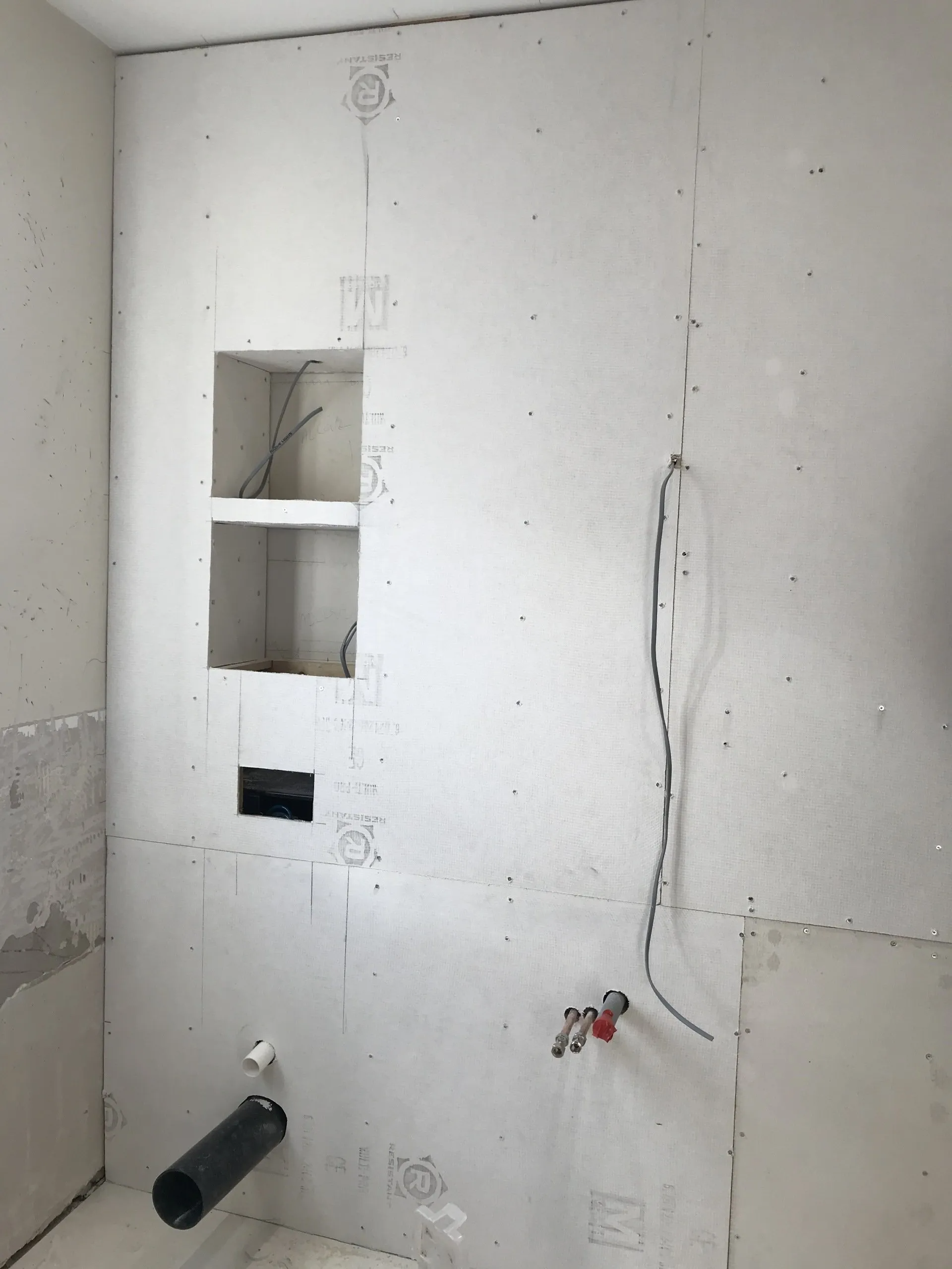 A white wall with a hole in it and a pipe coming out of it