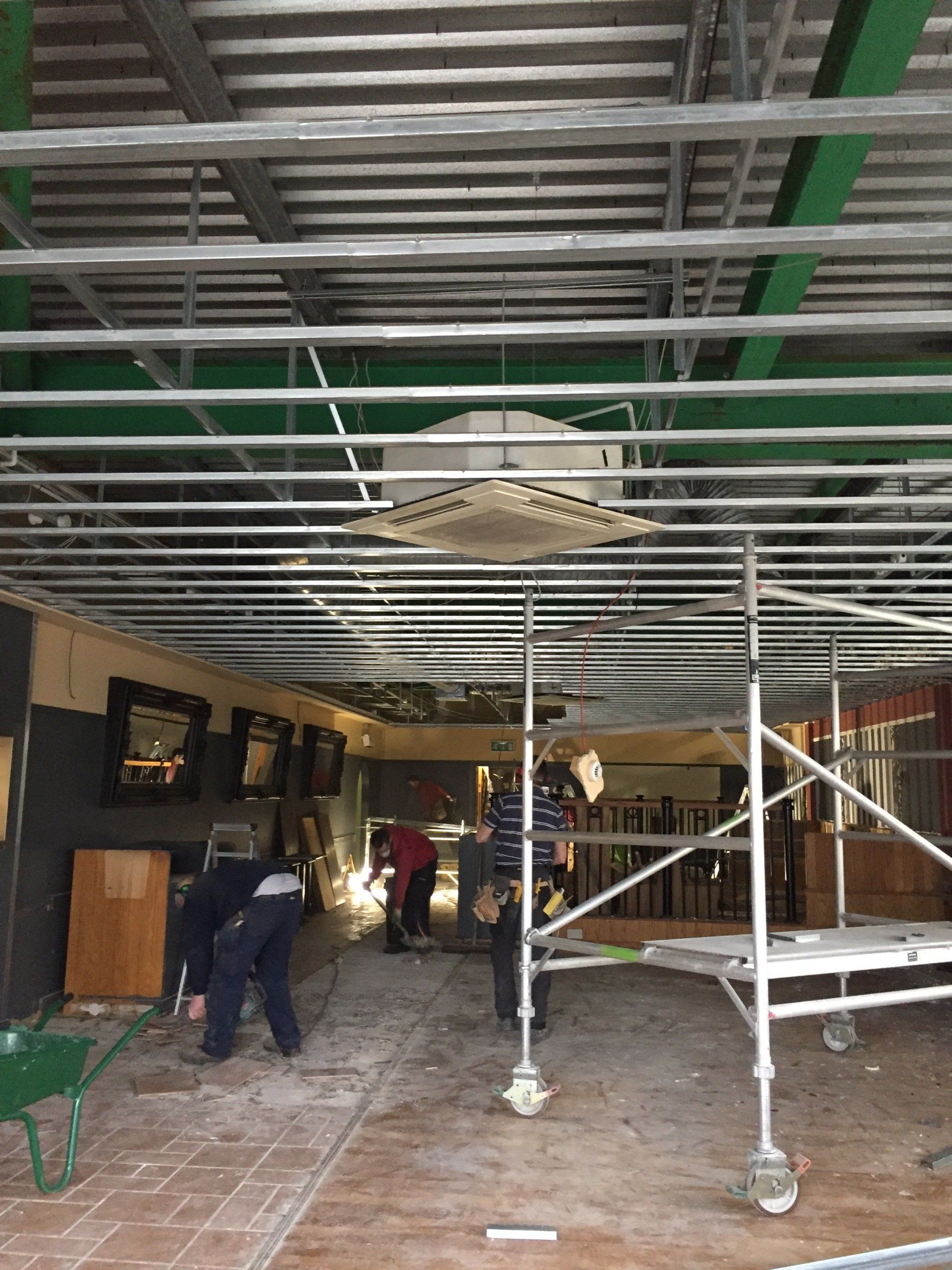 A group of people are working on the ceiling of a building.
