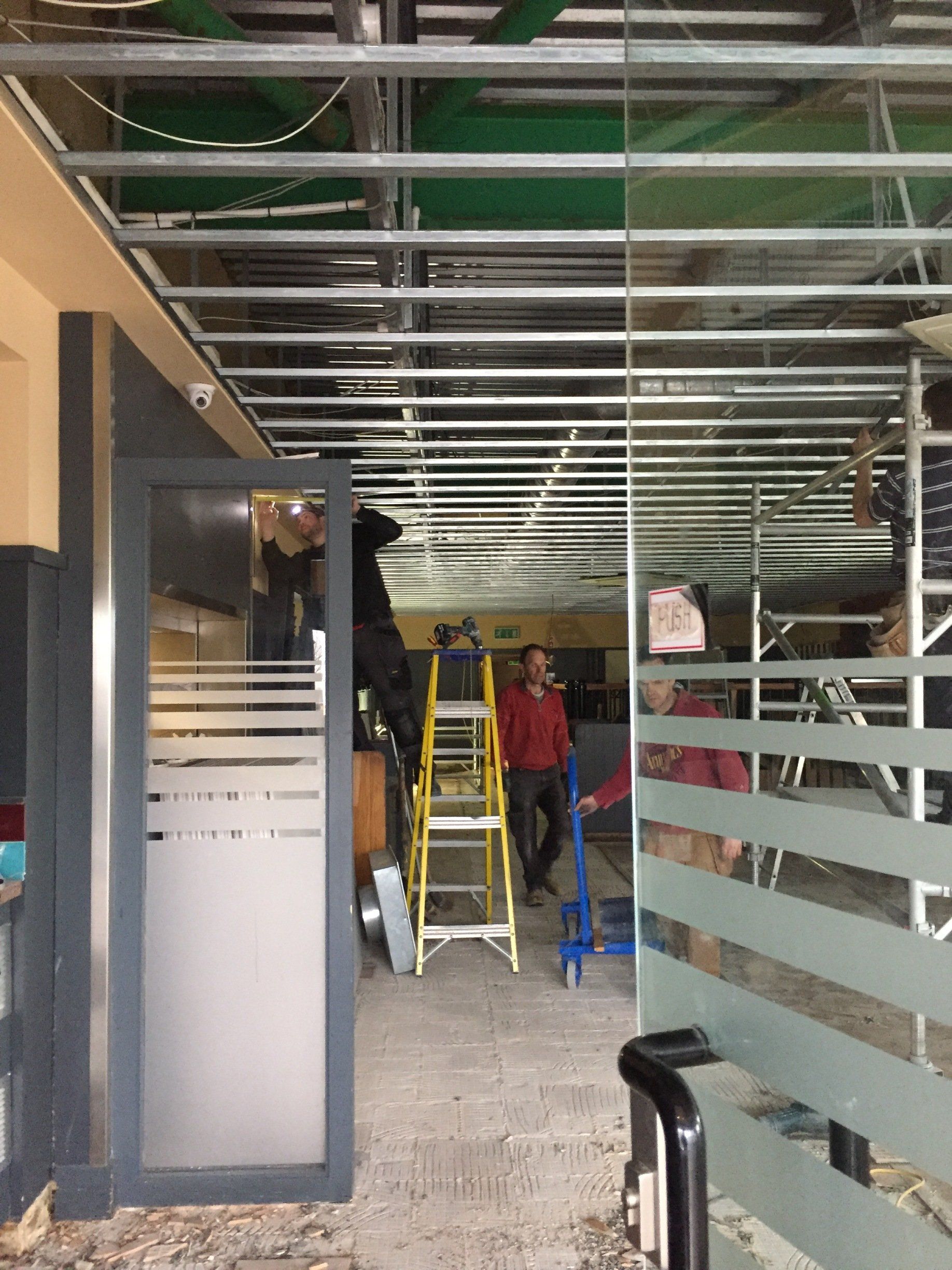 A group of people are working on the ceiling of a building.