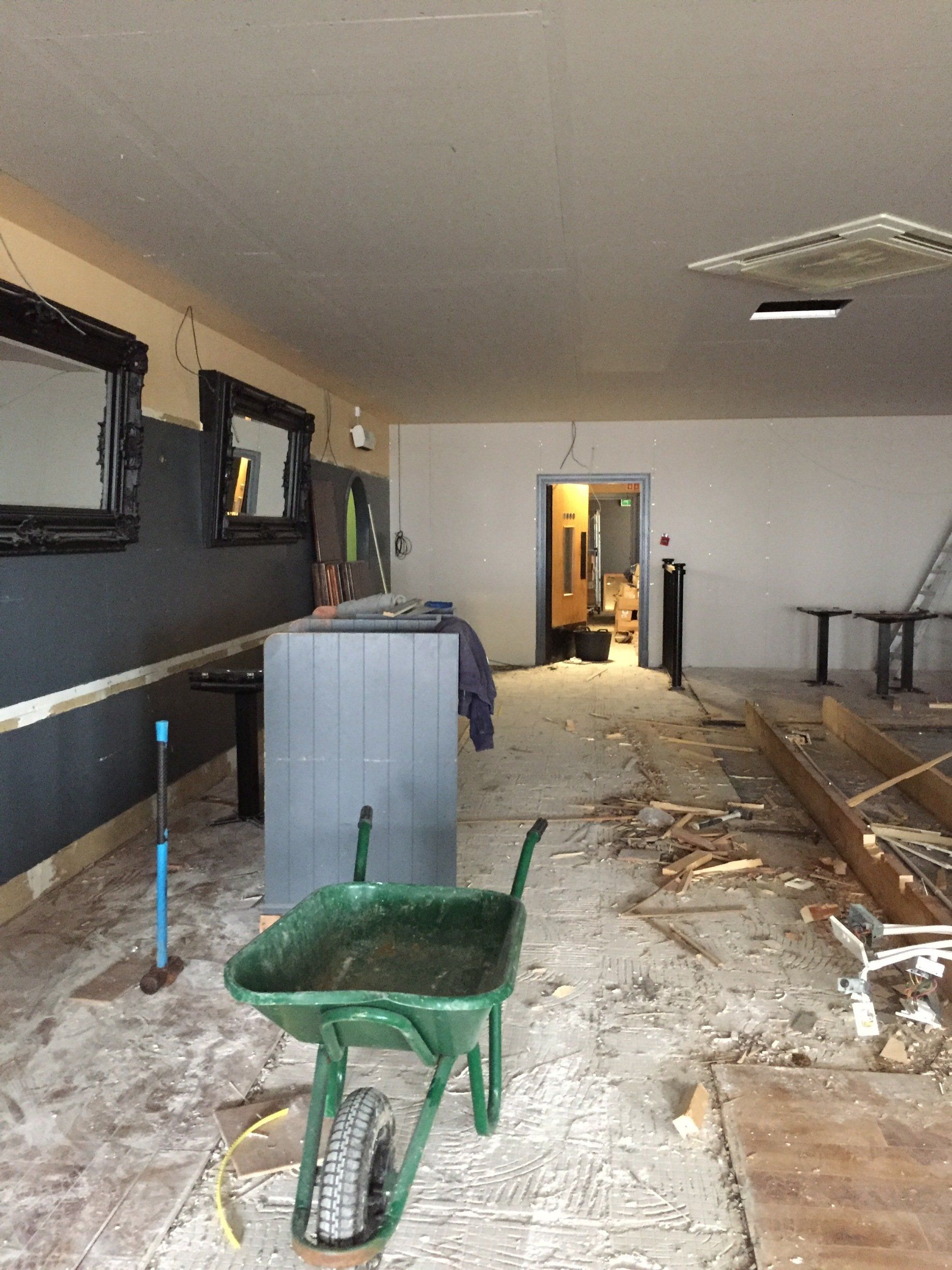 There is a green wheelbarrow in the middle of the room.