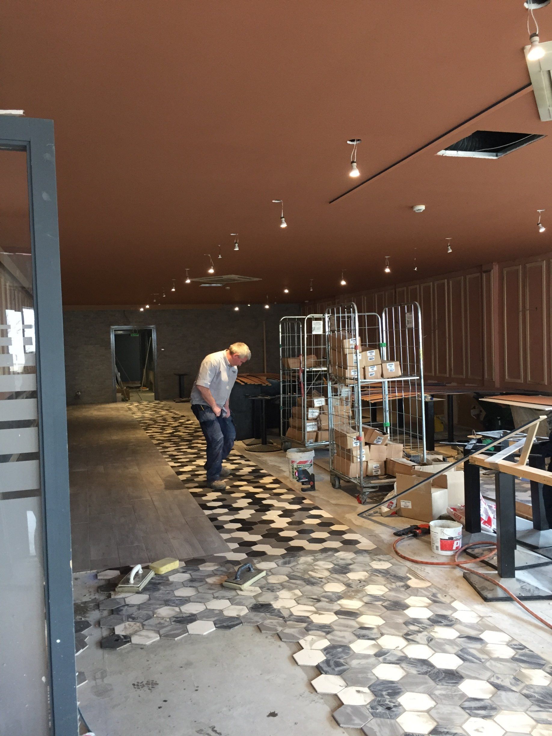 A man is working on a tiled floor in a room.