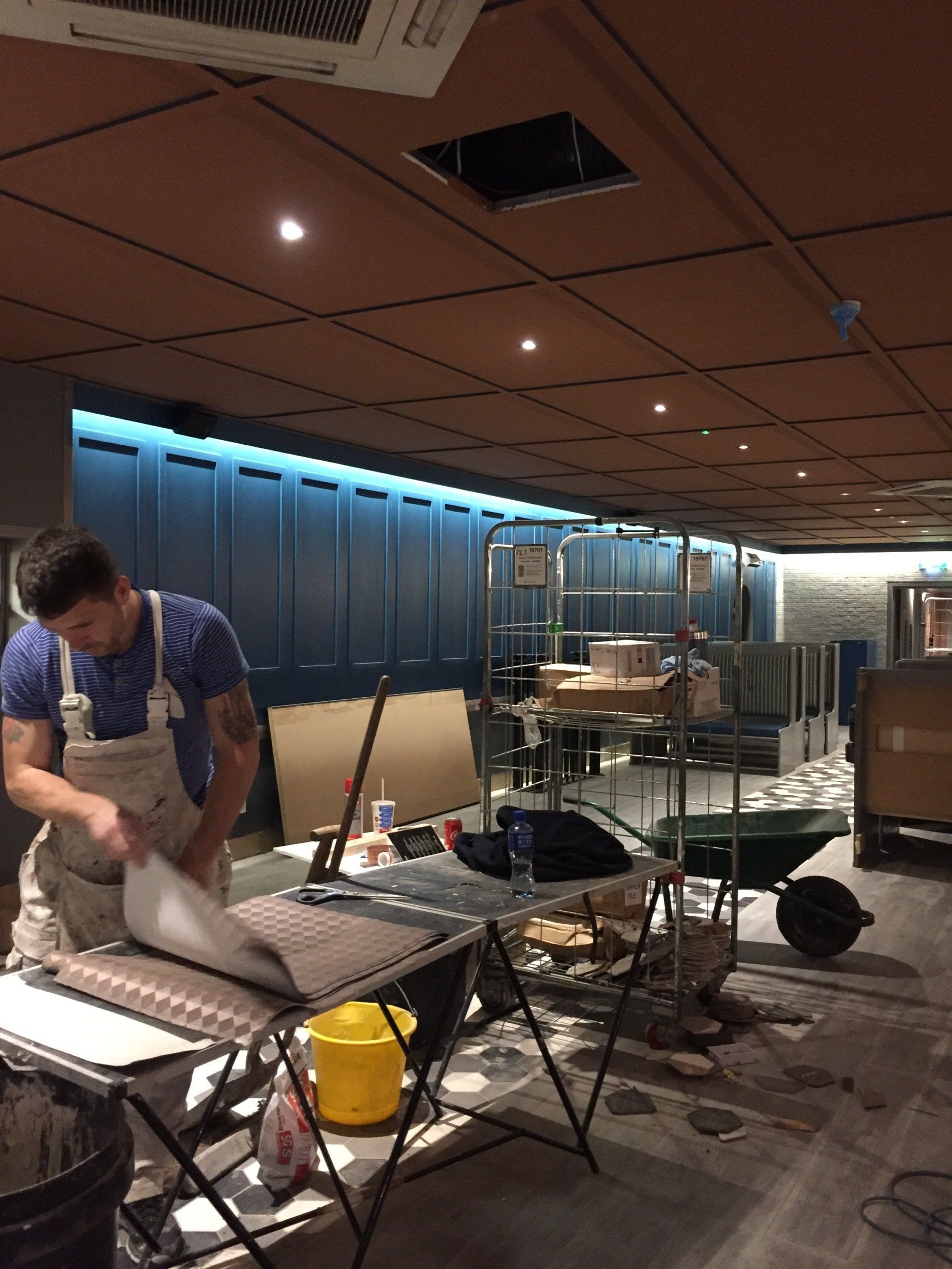 A man in overalls is working on a table in a room.