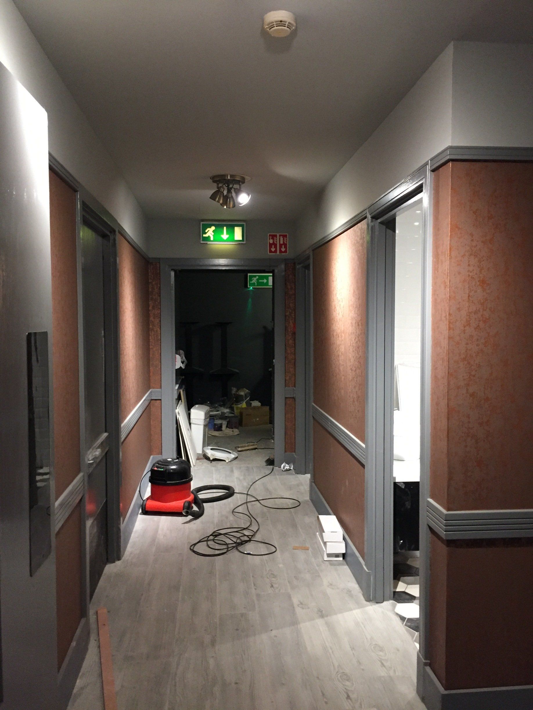 A long hallway with a red vacuum cleaner on the floor