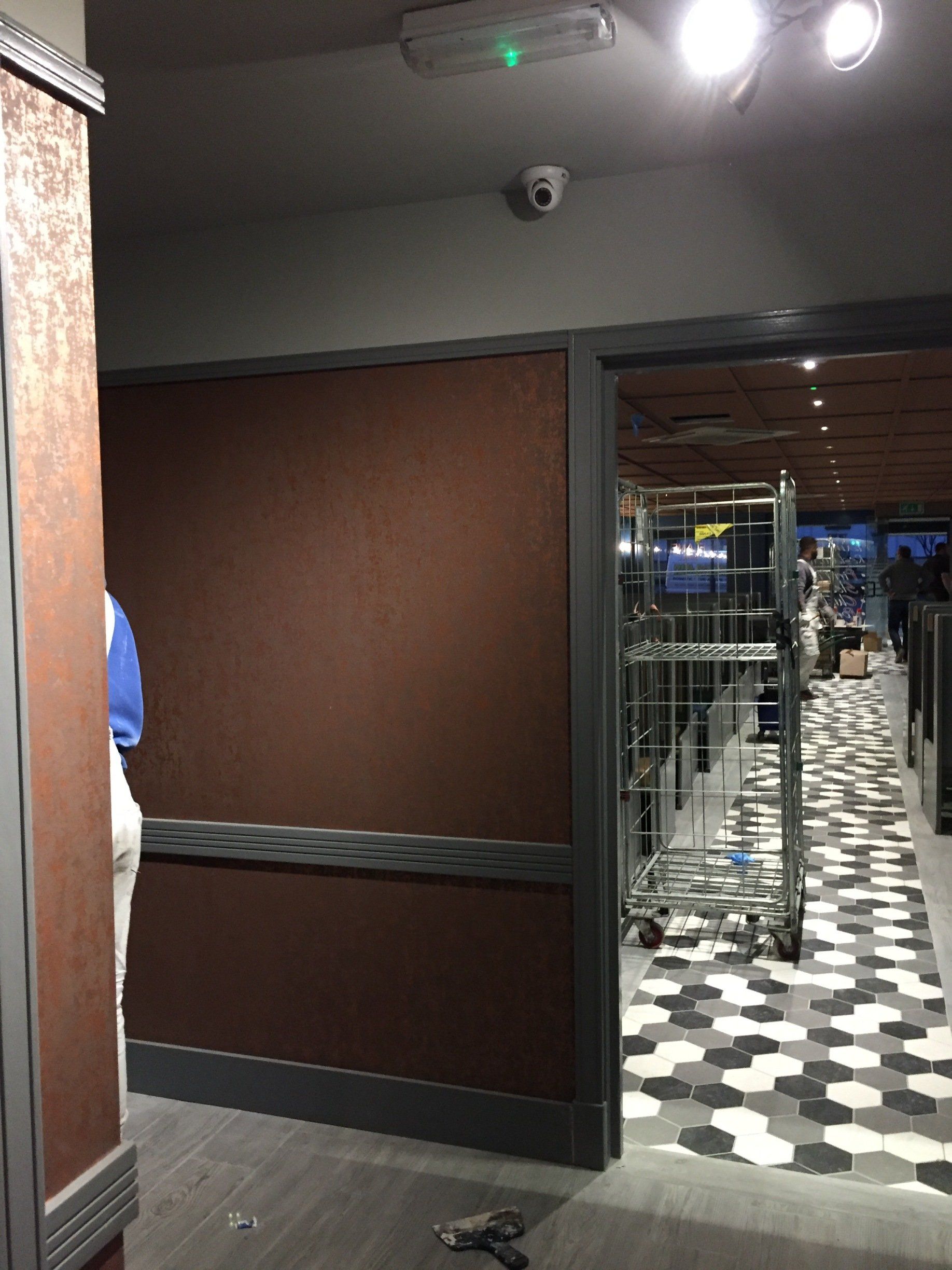 A hallway with a checkered floor and a brown wall