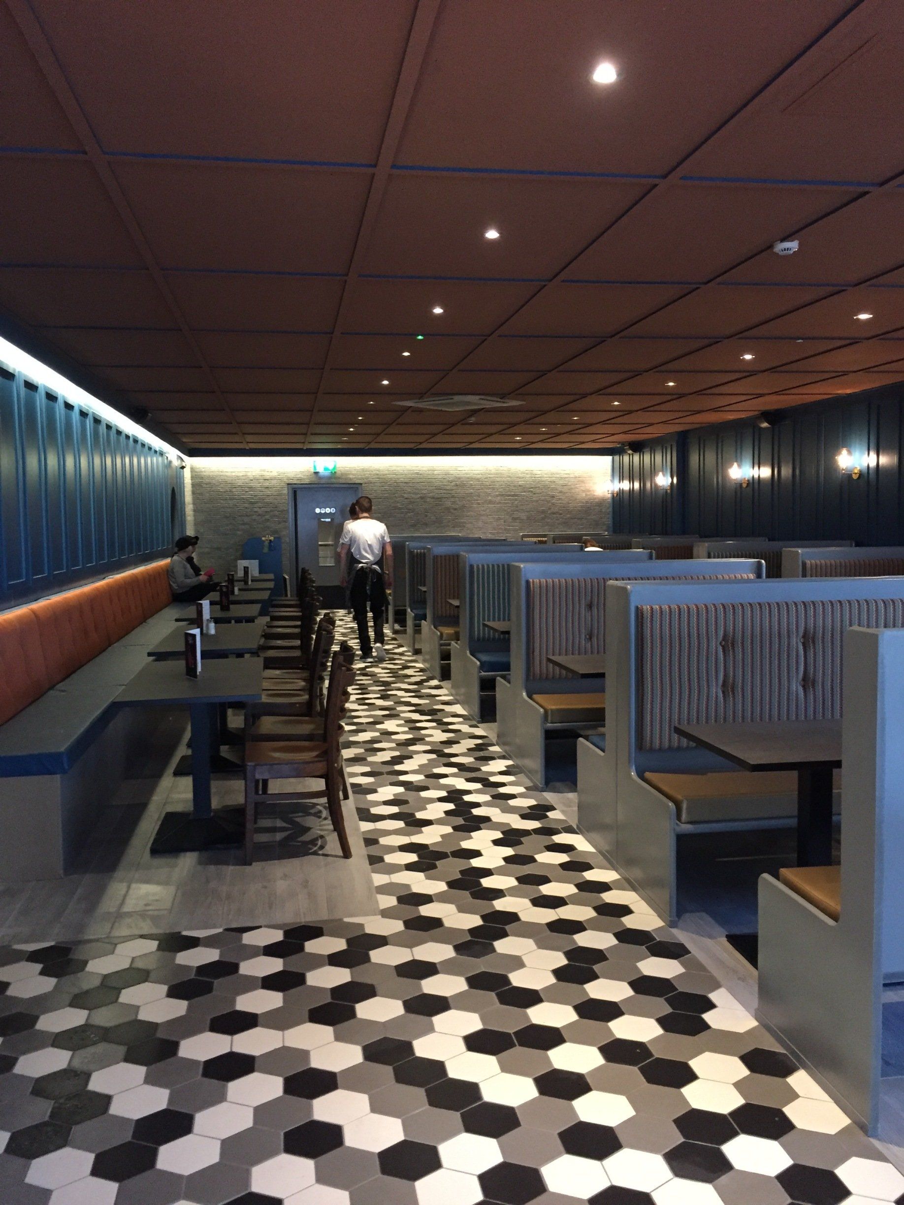 A restaurant with tables and benches and a patterned floor