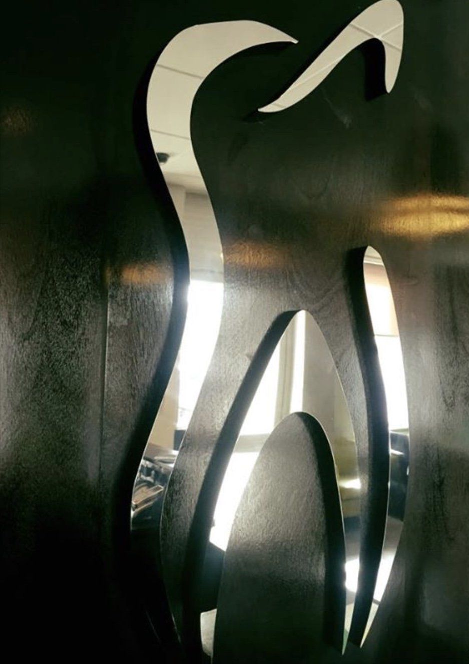 A silhouette of a tooth is cut out of a wall