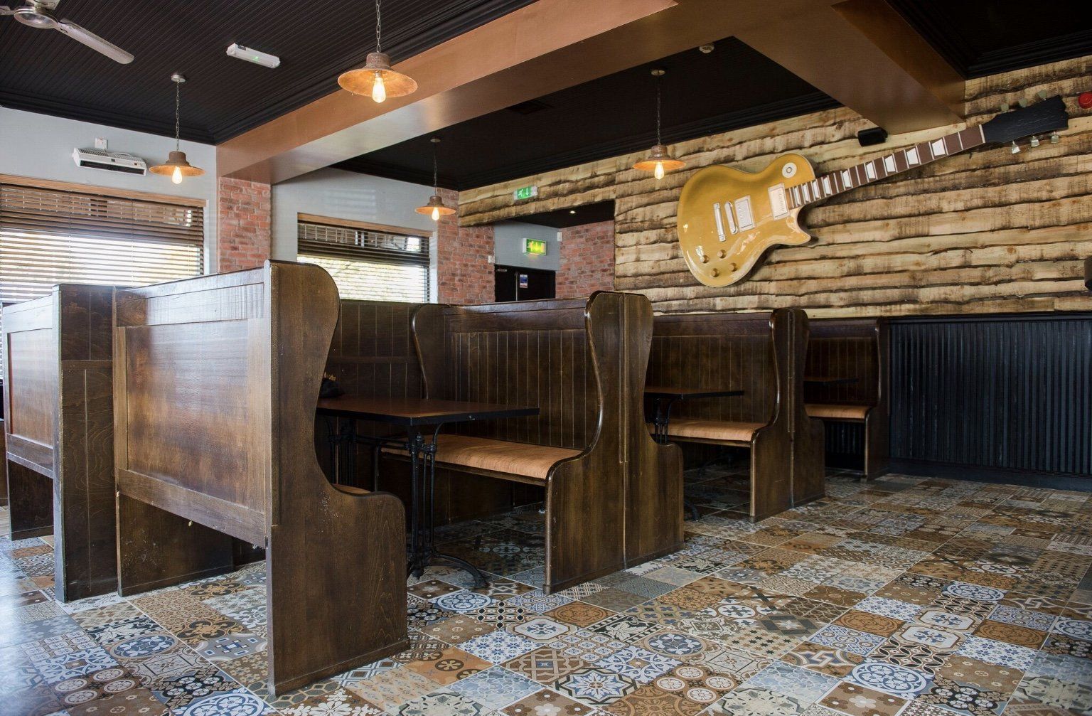 A guitar is hanging on a brick wall in a restaurant.