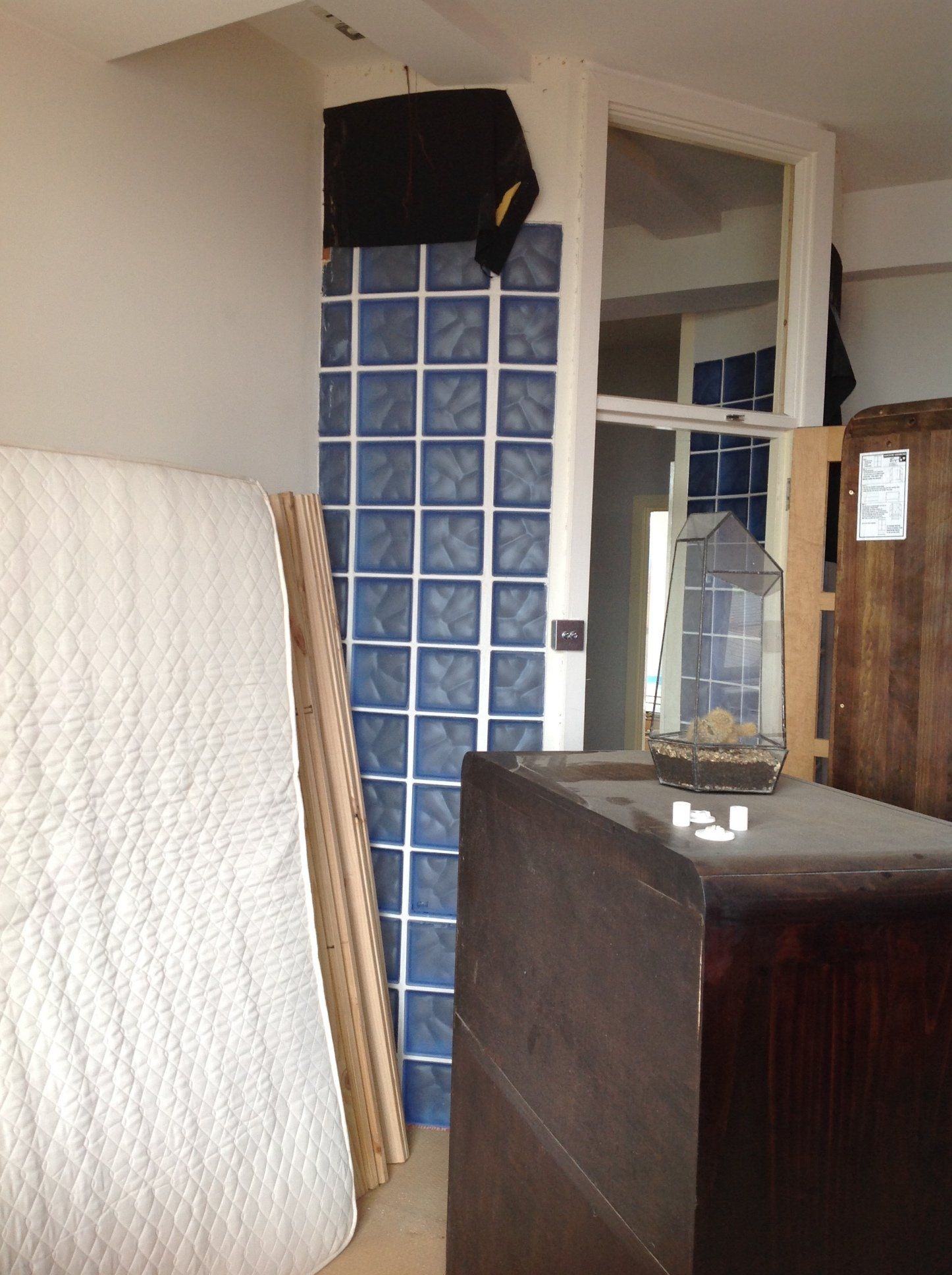 A room with a mattress and a bird cage