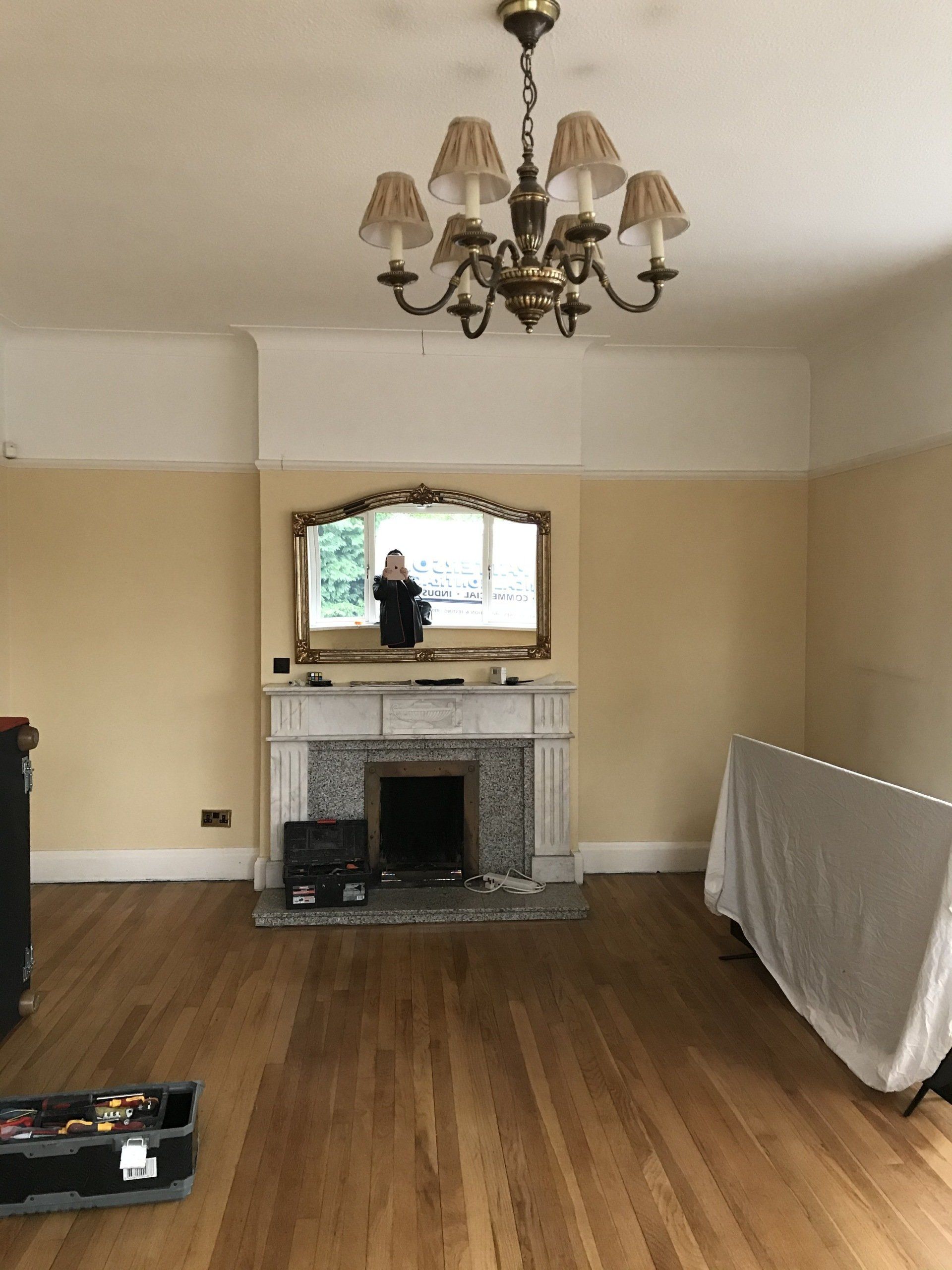 A living room with a fireplace , mirror and chandelier.