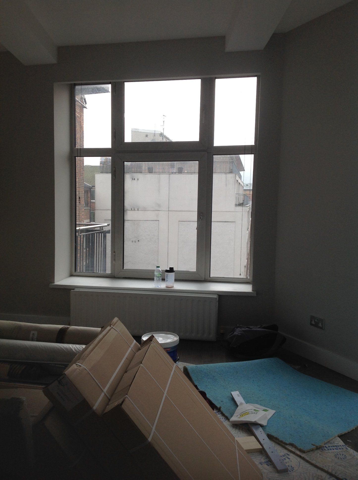 A room with a large window and boxes on the floor