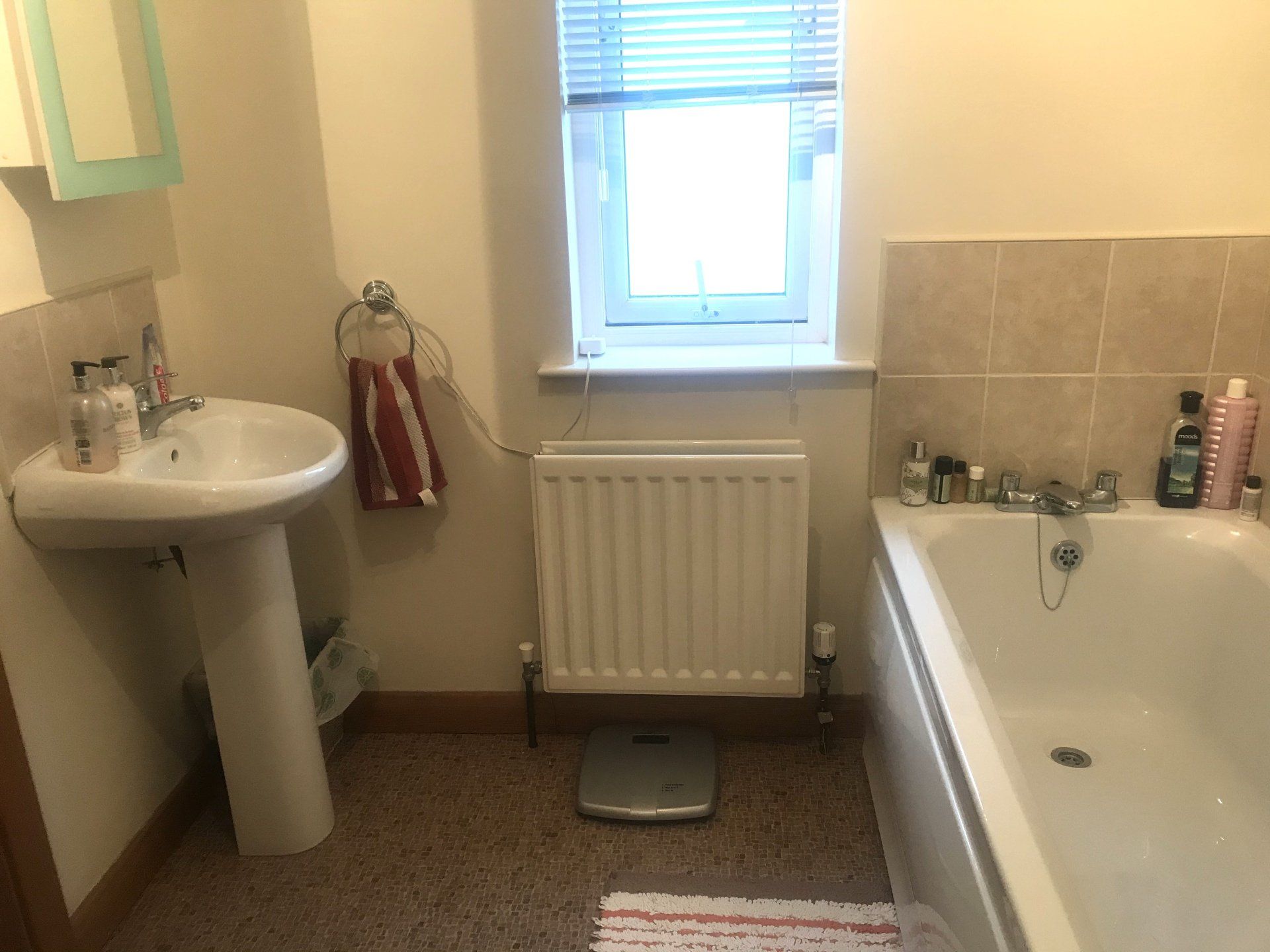 A bathroom with a sink , bathtub , and radiator.