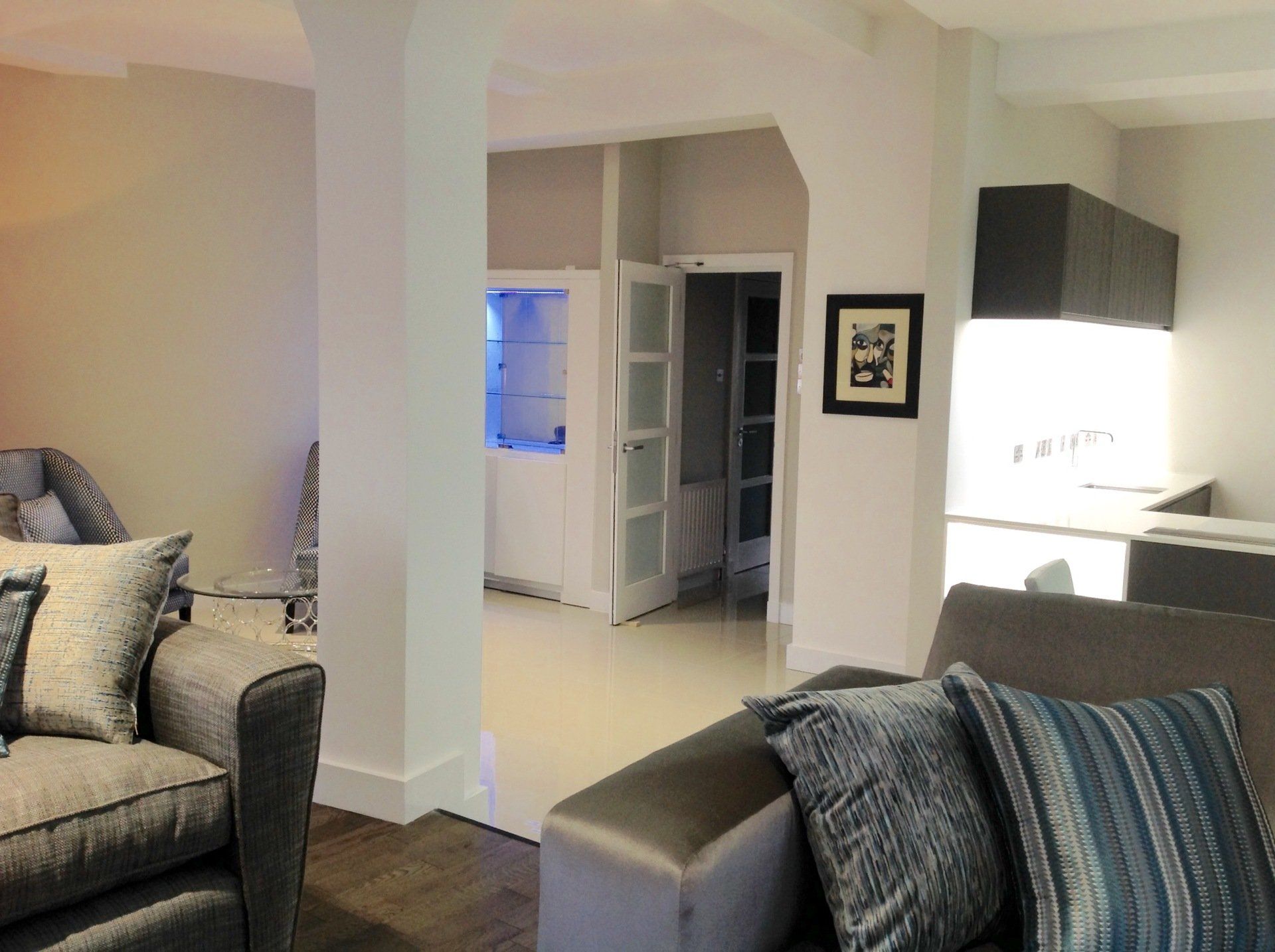 A living room with a couch and a chair and a picture on the wall.