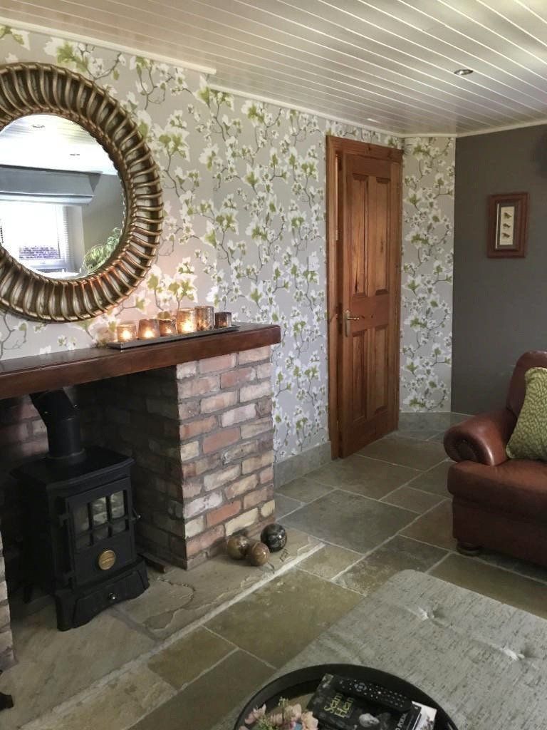 A living room with a fireplace , chair , table and mirror.