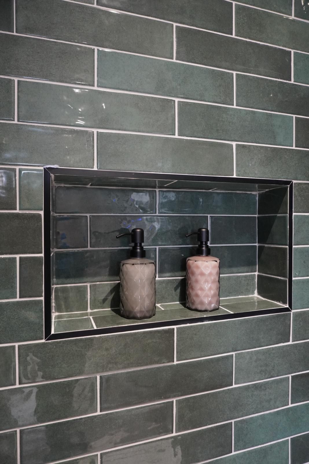 Two soap dispensers are sitting on a shelf in a bathroom.