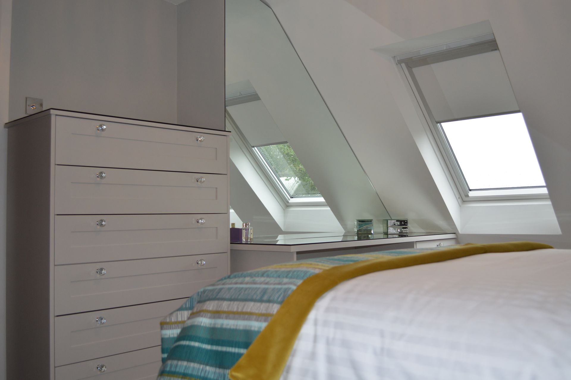 A bedroom with a bed , dresser , and skylight