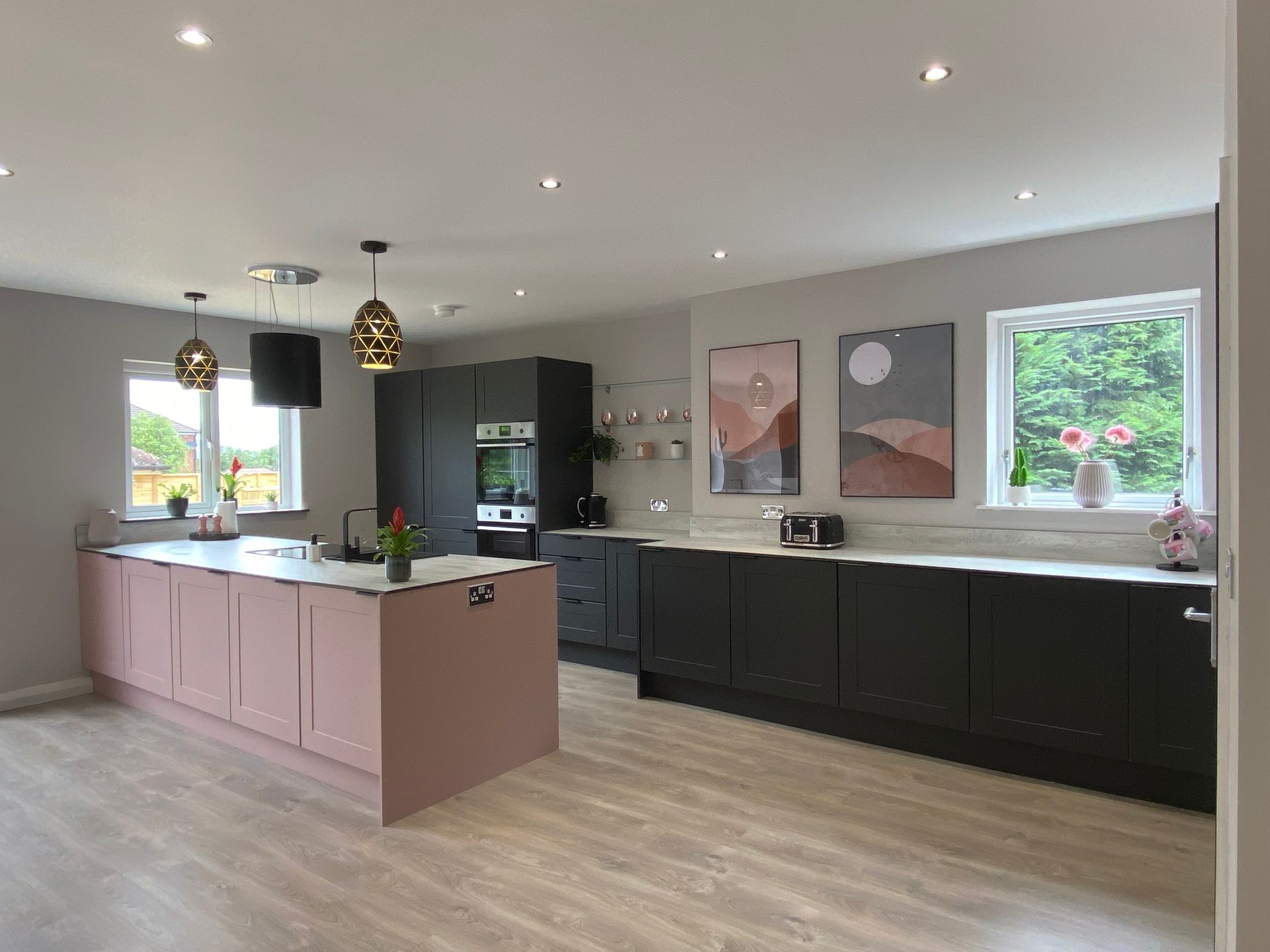 A large kitchen with pink cabinets and black cabinets and a large island in the middle.