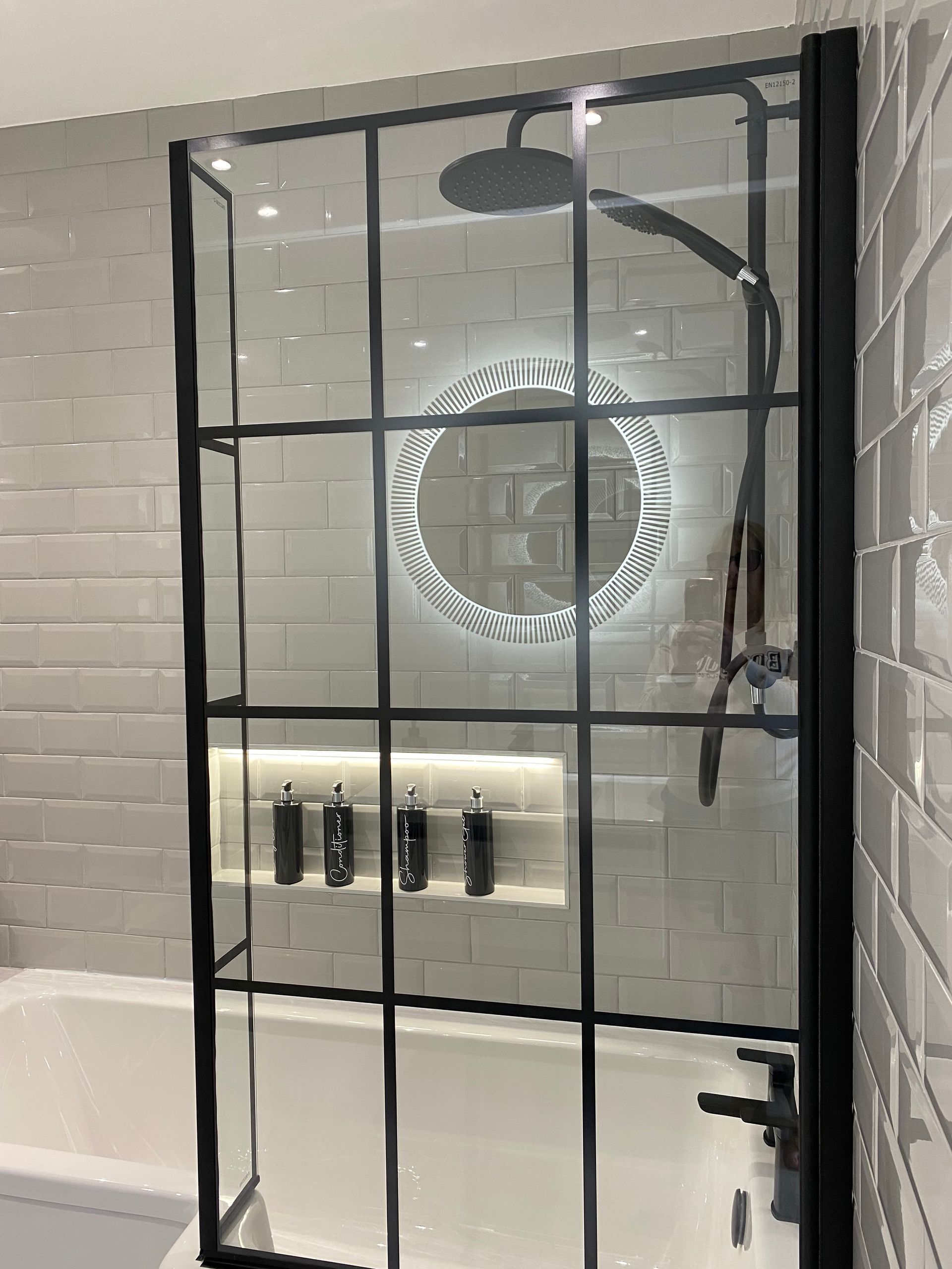 A bathroom with a bathtub and a shower stall with a black frame.