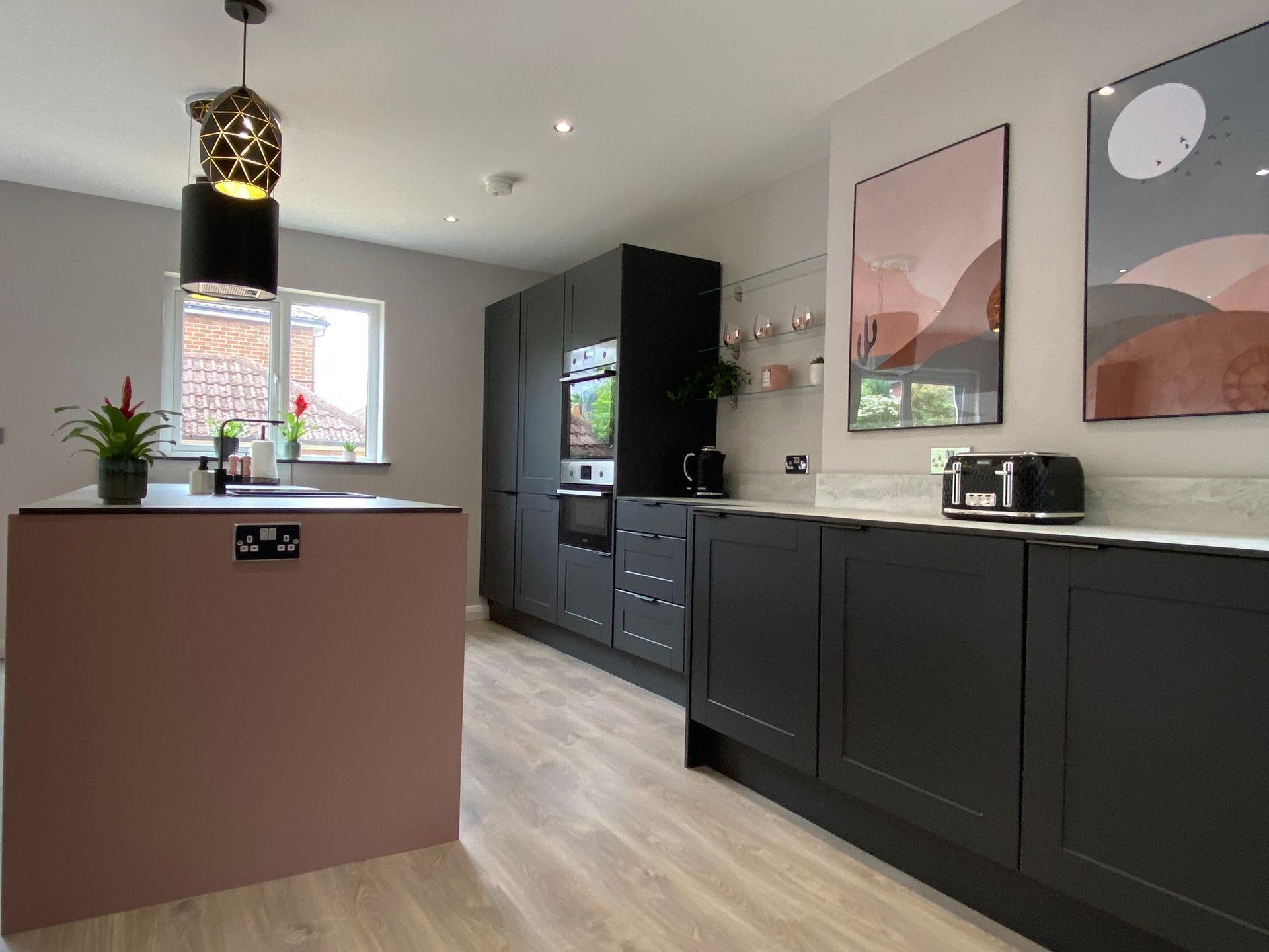 A kitchen with black cabinets and a pink island.