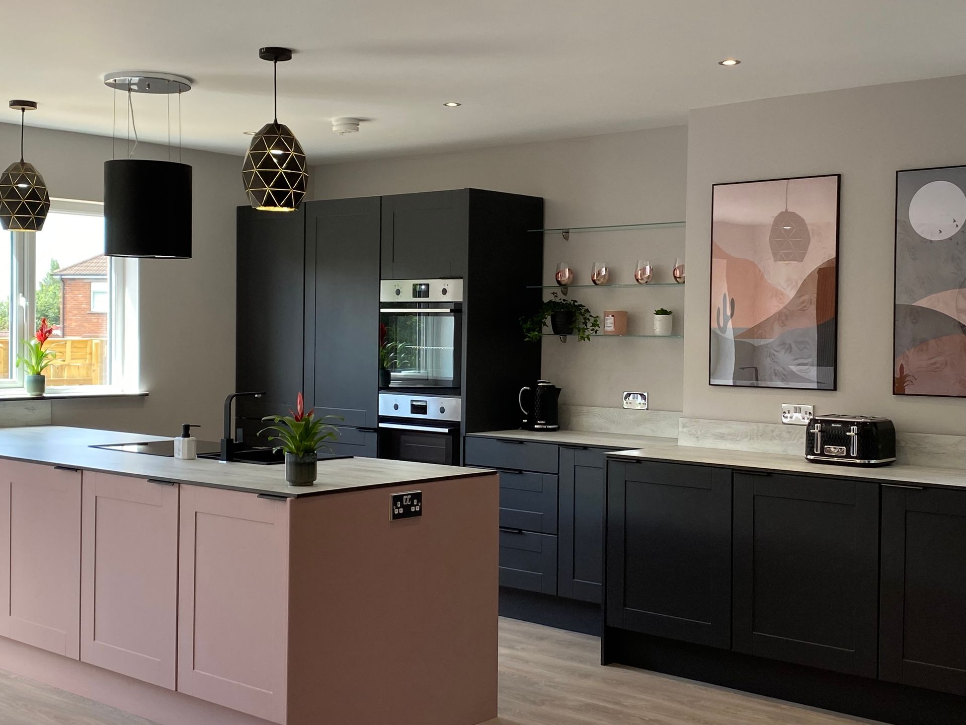A kitchen with black cabinets and a pink island.