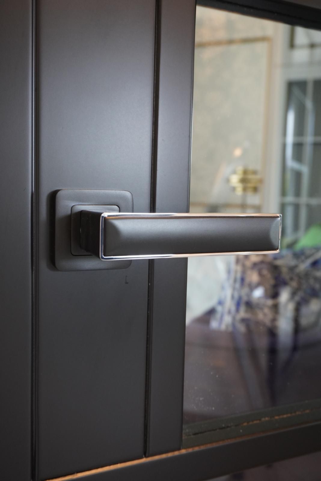 A close up of a black door handle on a glass door.