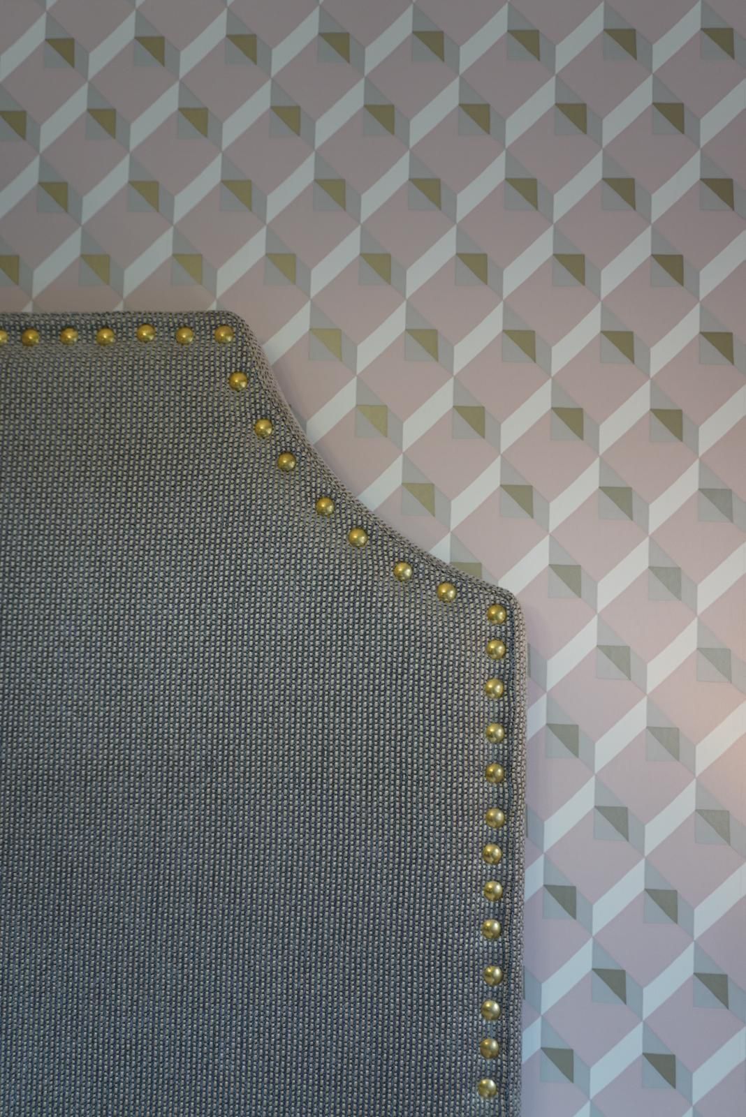 A headboard is sitting in front of a wall with a geometric pattern.