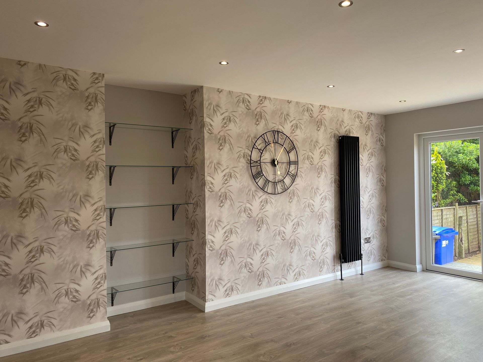 A living room with a clock on the wall and shelves.
