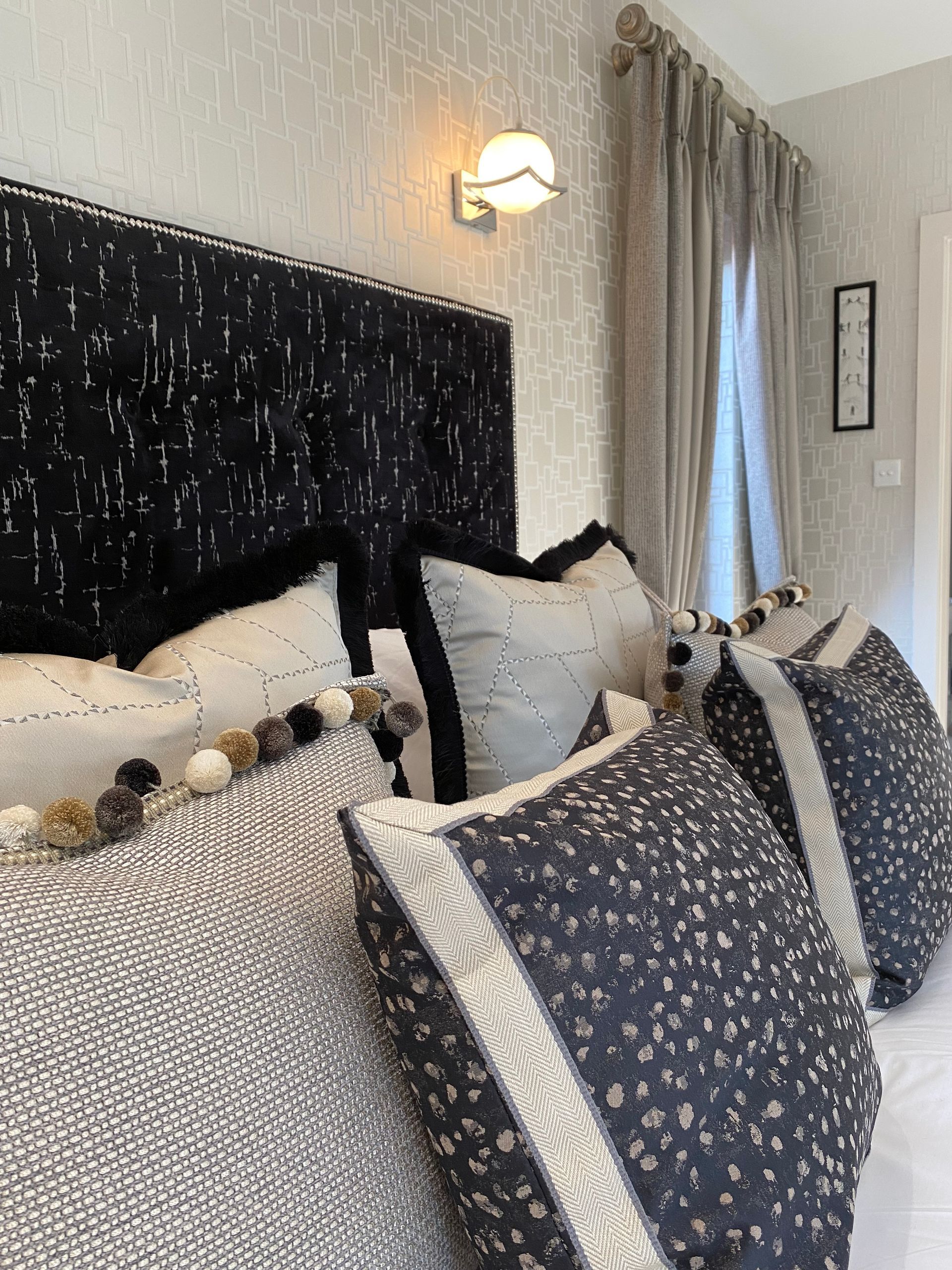 A bed with lots of pillows and a headboard in a bedroom.