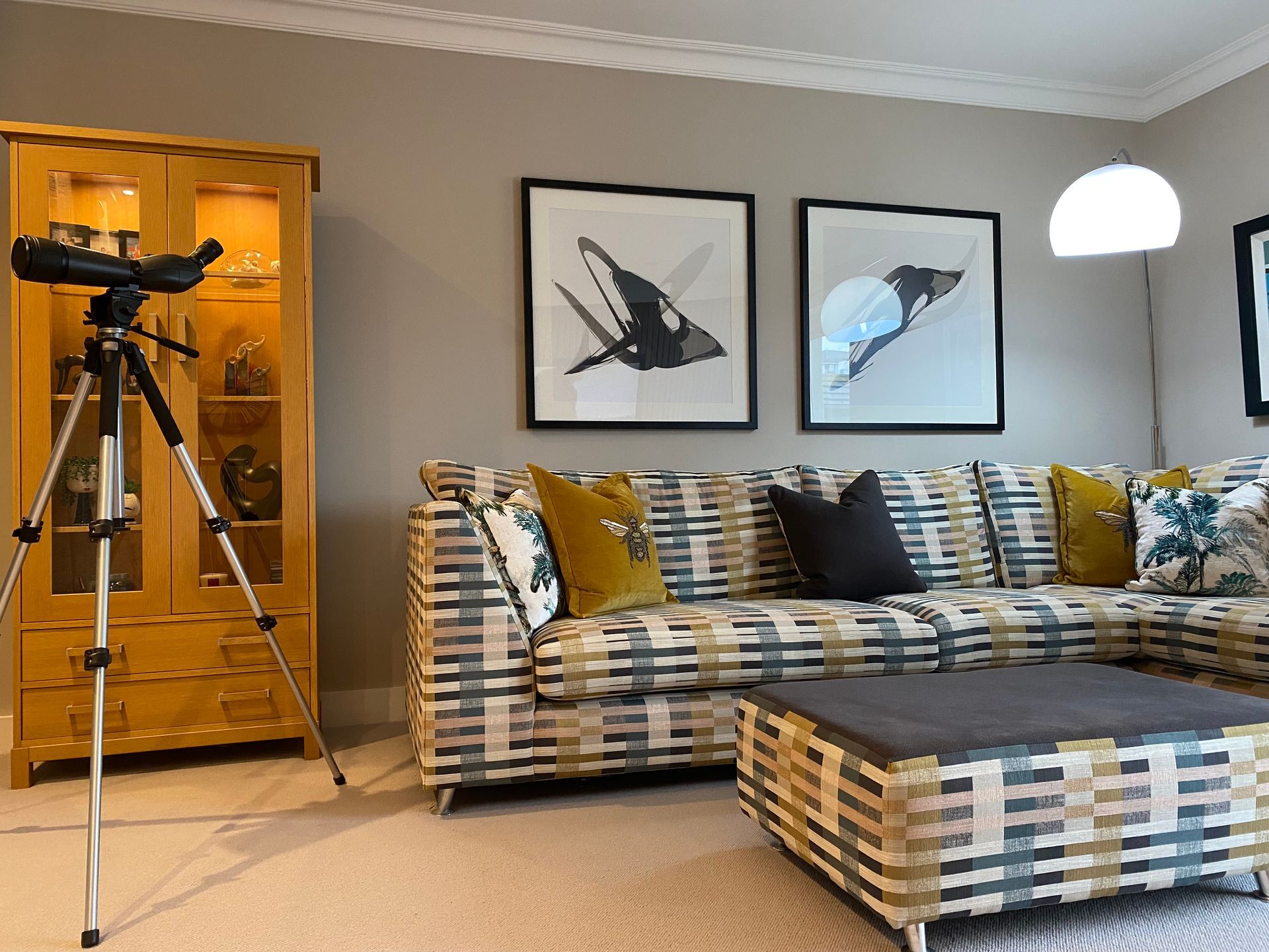A living room with a couch , ottoman , and a telescope.