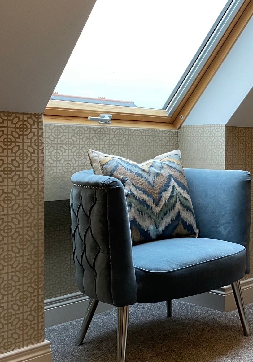 A chair with a pillow on it is sitting under a skylight in a room.