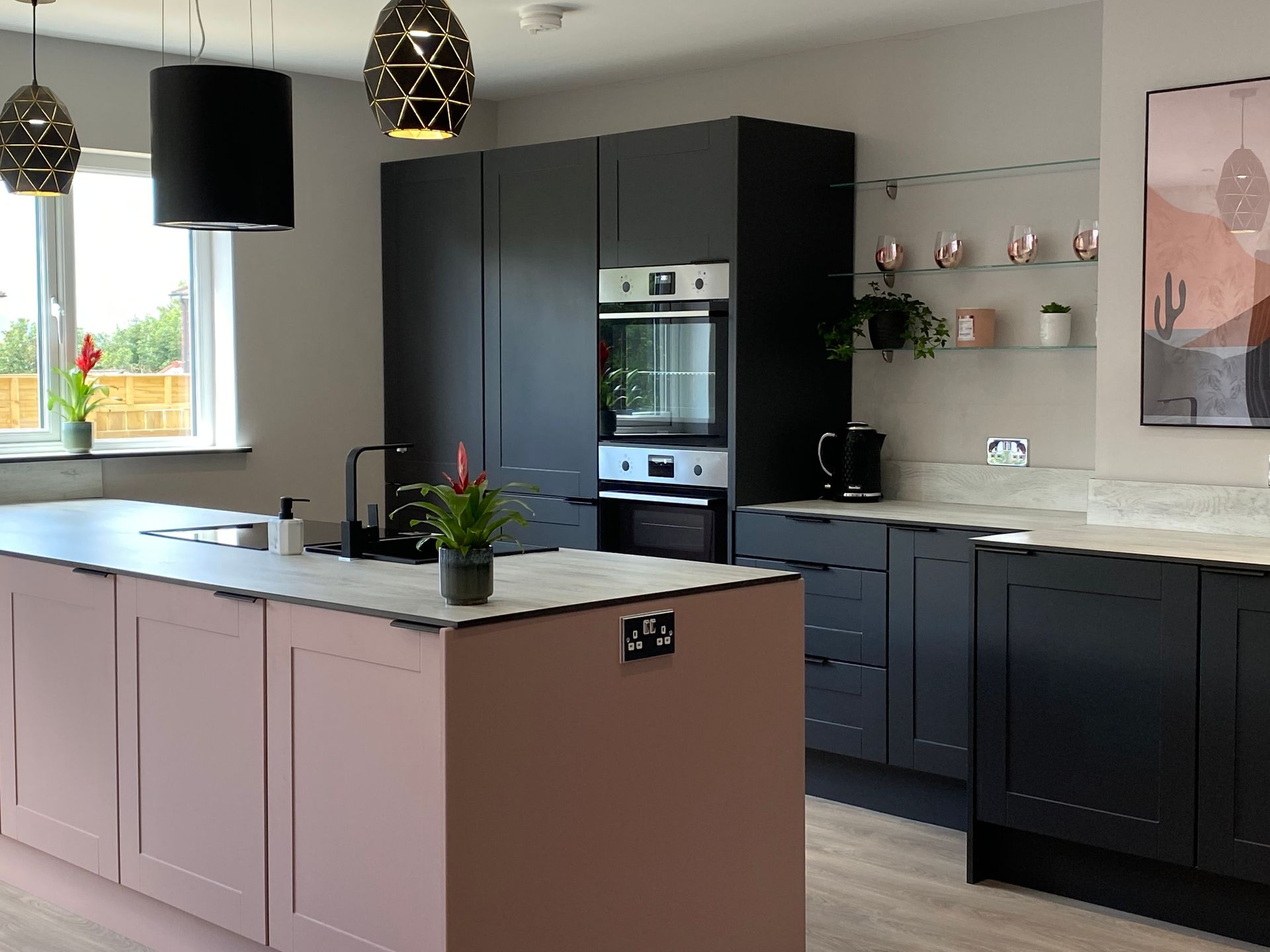 A kitchen with black cabinets and a pink island